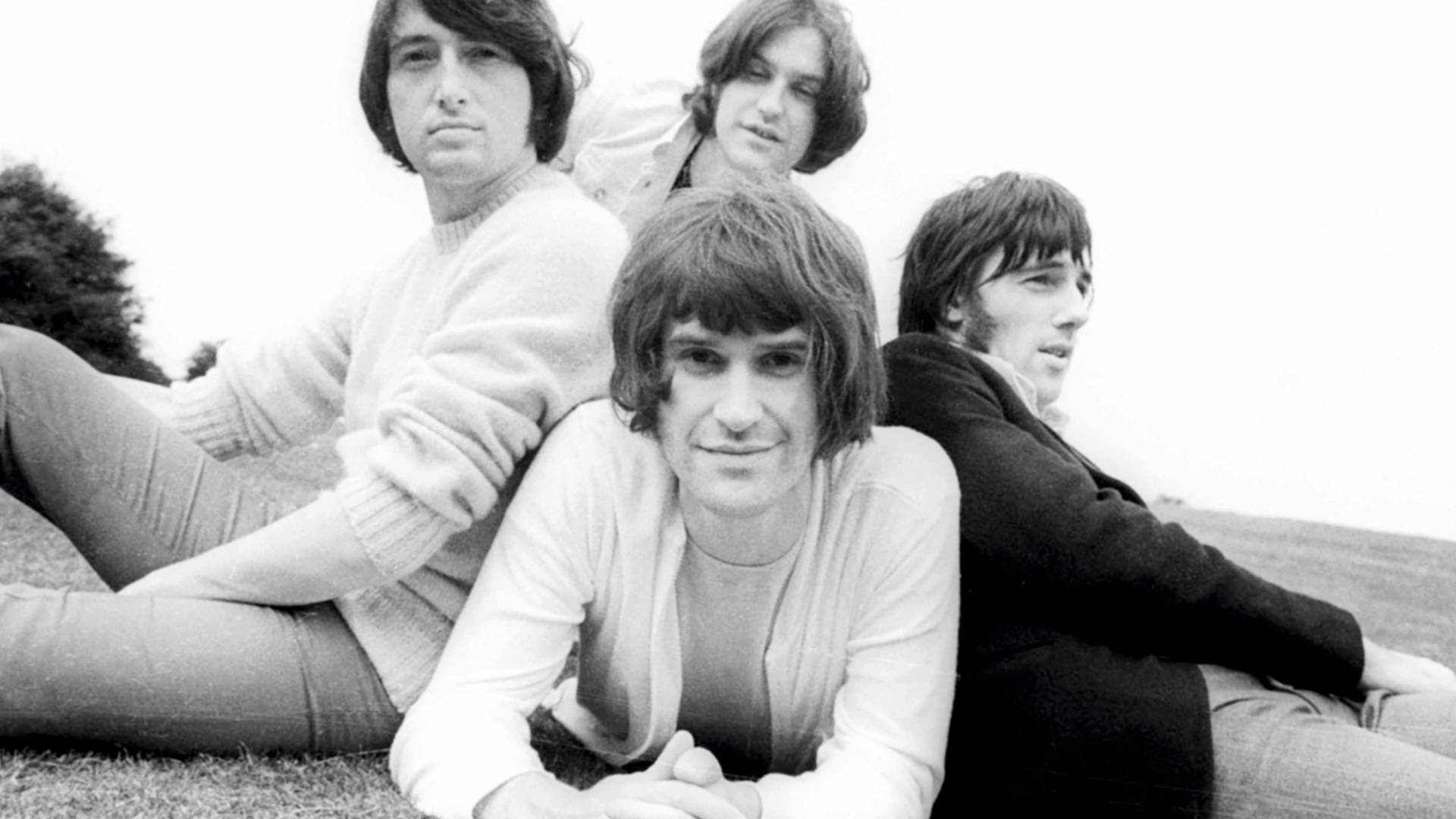 The Kinks 戶外復古海報 壁紙 — 四位長髮男士隨意坐在草地上，一張復古黑白照片。