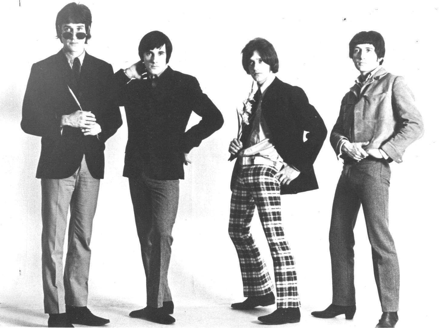 The Kinks黑白海報 壁紙 — 四位身穿1960年代摩登時尚的男士，在純白背景前自信地擺姿勢，經典黑白工作室肖像。