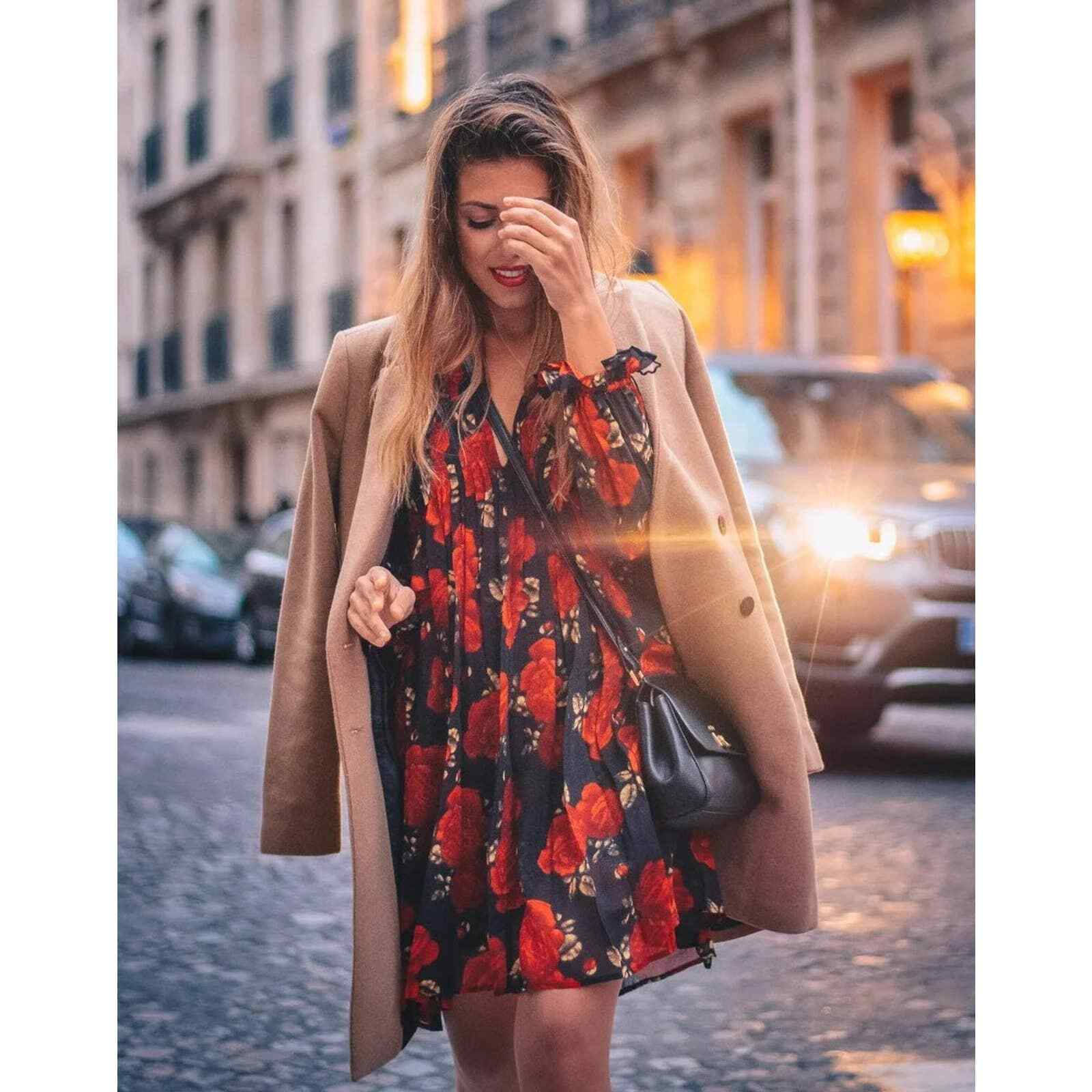 穿著花卉連衣裙和外套的女性在黃金時段走在城市街道上。