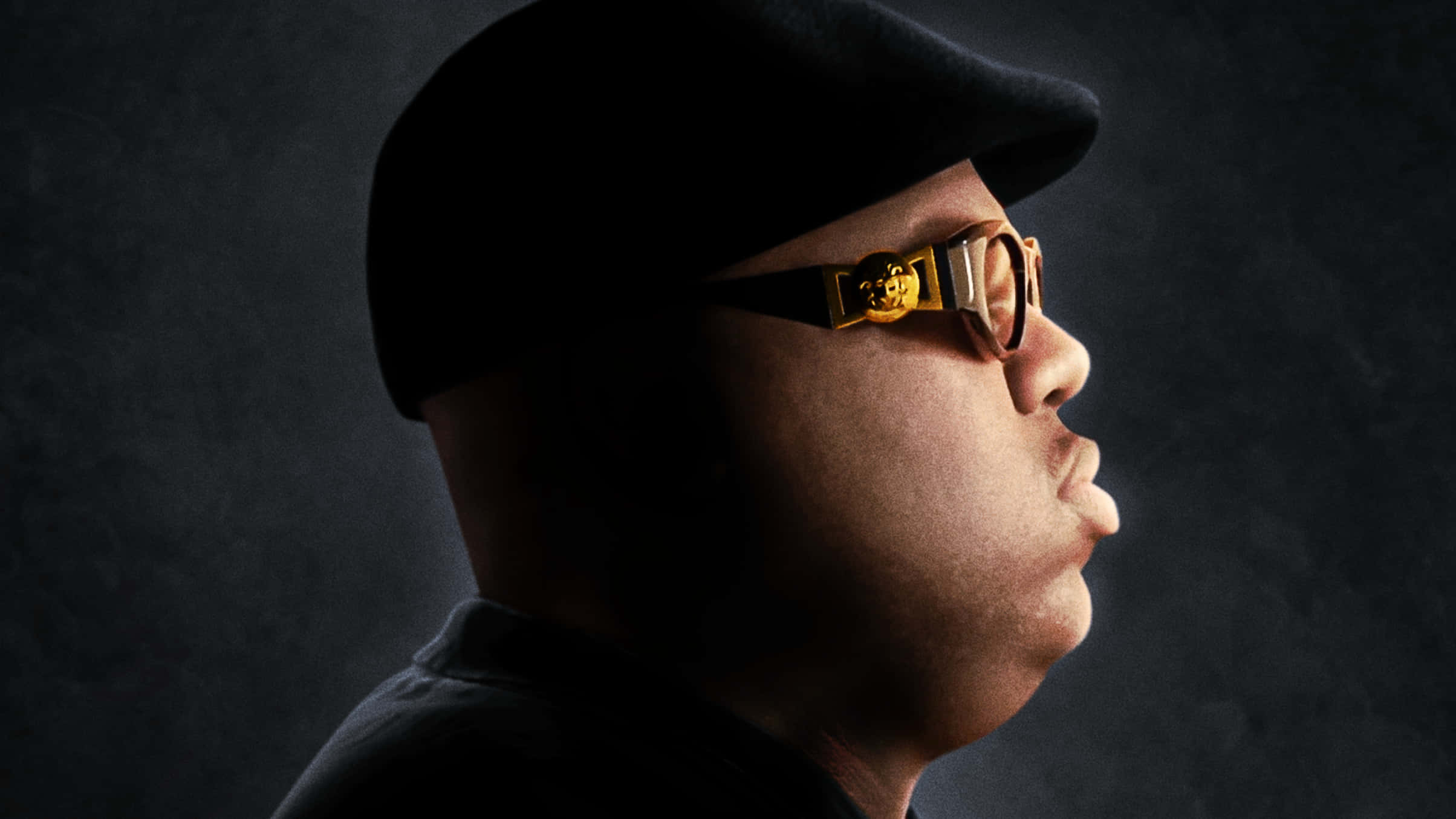 The Notorious B.I.G. 側臉剪影 壁紙 — 一名戴著黑色帽子和金色邊框眼鏡的男性側面，背景為深色紋理。