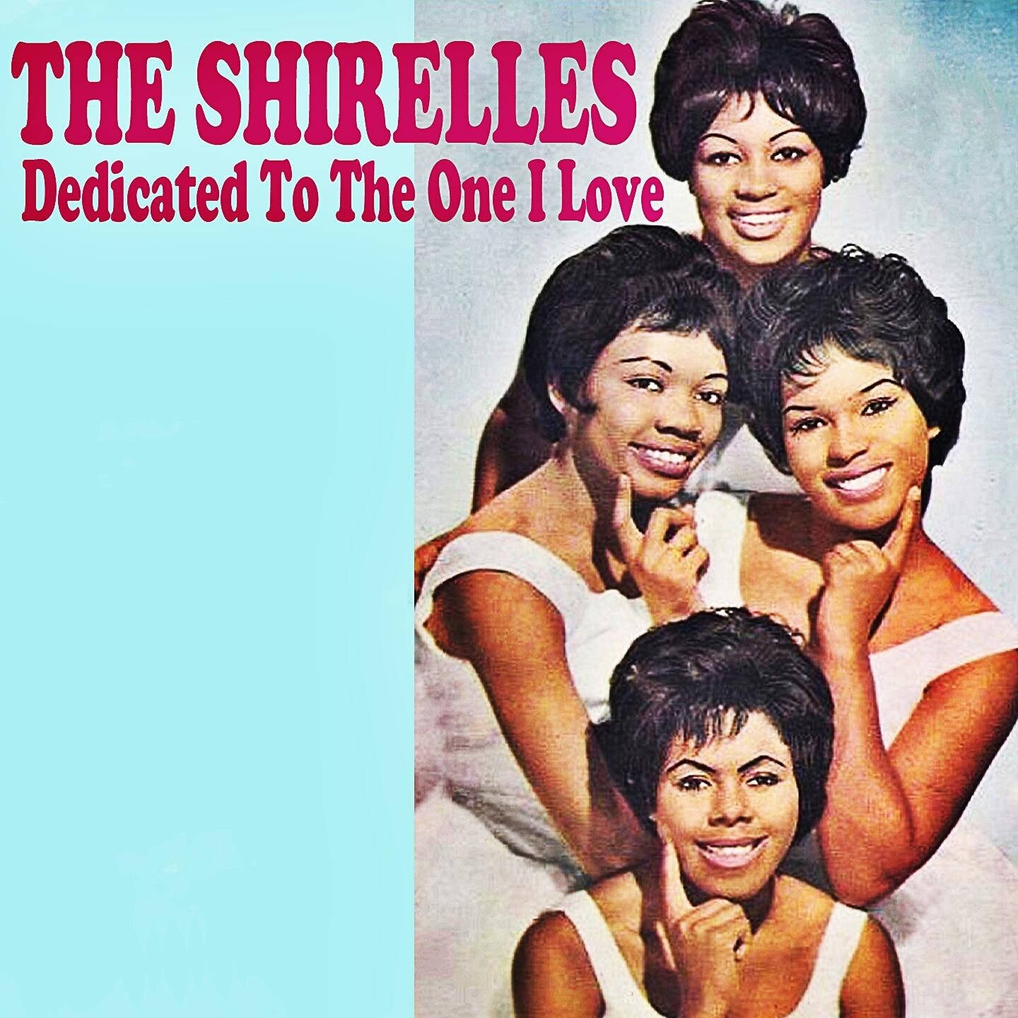 The Shirelles《Dedicated To The One I Love》1960 歌曲封面 壁紙 — 四位穿著白色連衣裙的微笑女性在淺藍色背景前擺姿勢，上面有粗體粉紅色文字寫著「THE SHIRELLES Dedicated To The One I Love」。
