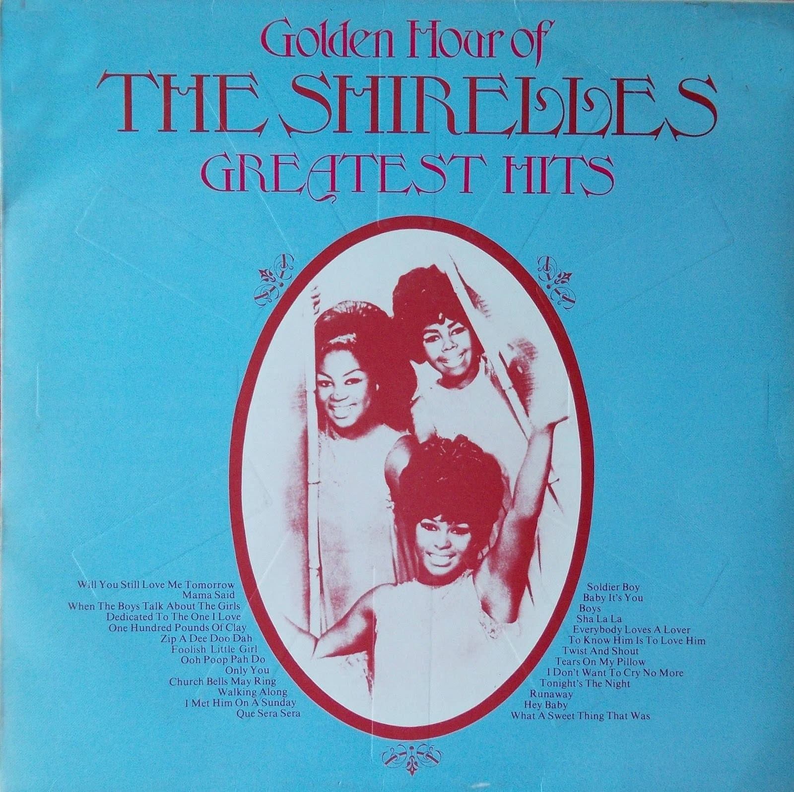 The Shirelles《Golden Hour of Greatest Hits》1973 專輯封面 壁紙 — The Shirelles' Greatest Hits 的復古專輯封面，藍色背景上有一個紅色橢圓形，內有三個微笑的女性。