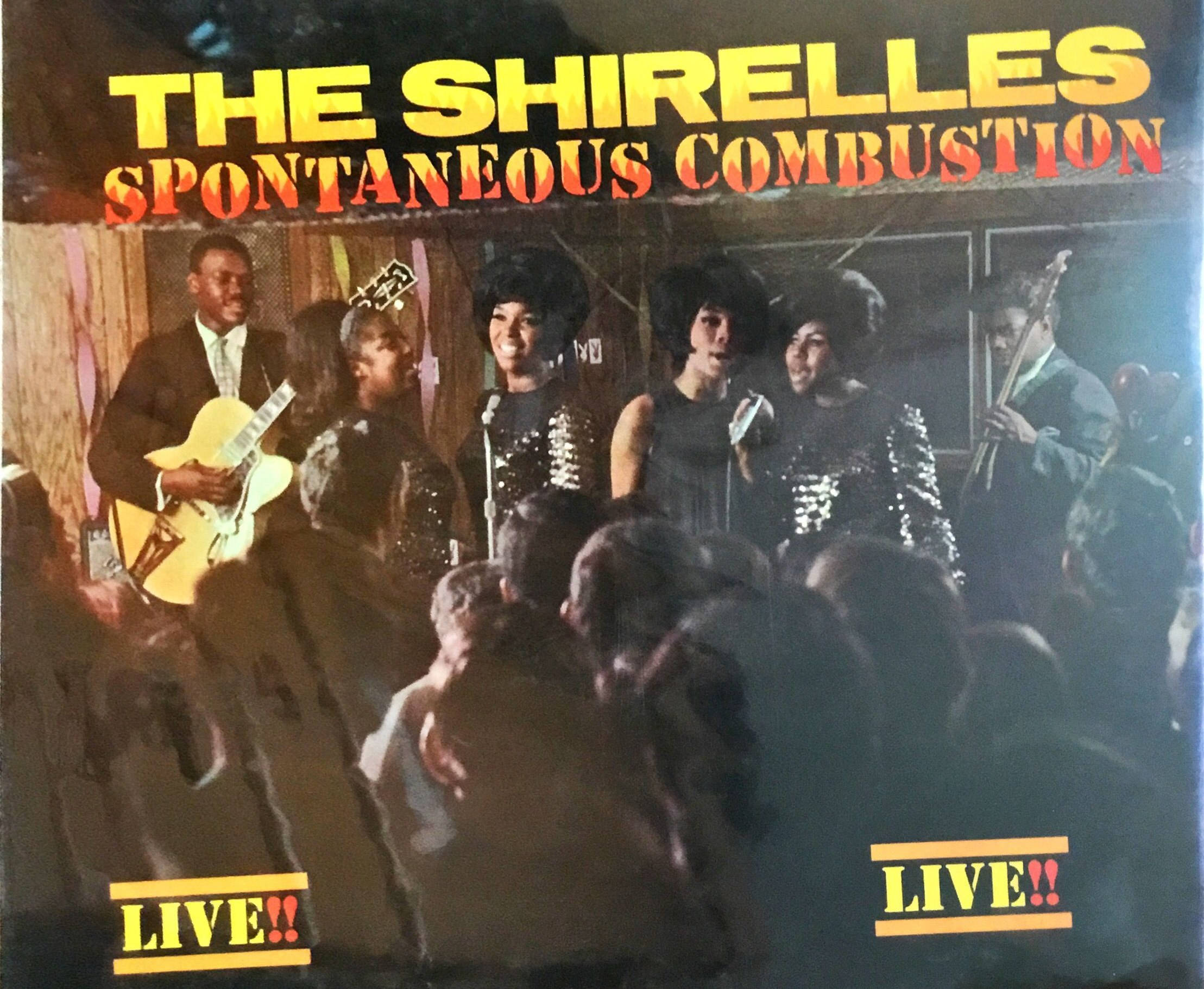 The Shirelles《Spontaneous Combustion》專輯封面 壁紙 — The Shirelles 的復古現場表演海報，描繪樂隊和人群在溫暖的舞台燈光下。