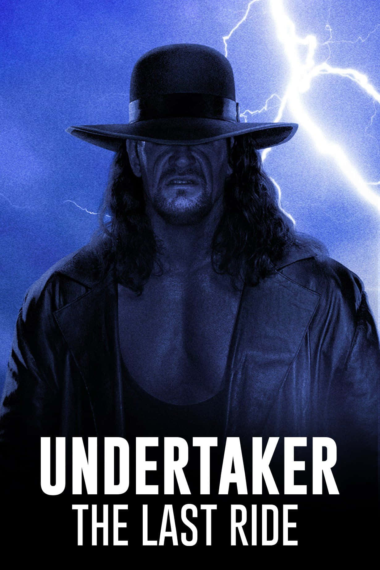  壁紙 — The Undertaker 戴著深色帽子和皮褸，在明亮的閃電劃破暴風雨藍天的背景下，威風凜凜地站立。