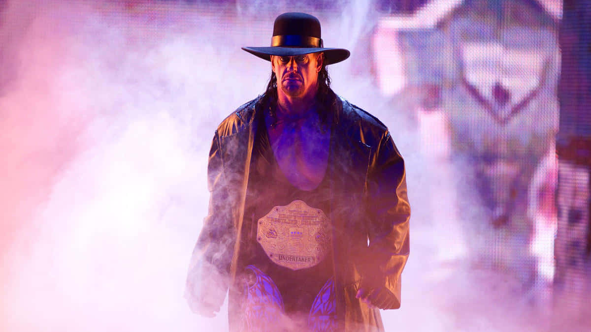  壁紙 — The Undertaker 穿過煙霧彌漫的紫色和粉紅色燈光，戴著他的標誌性帽子和冠軍腰帶。