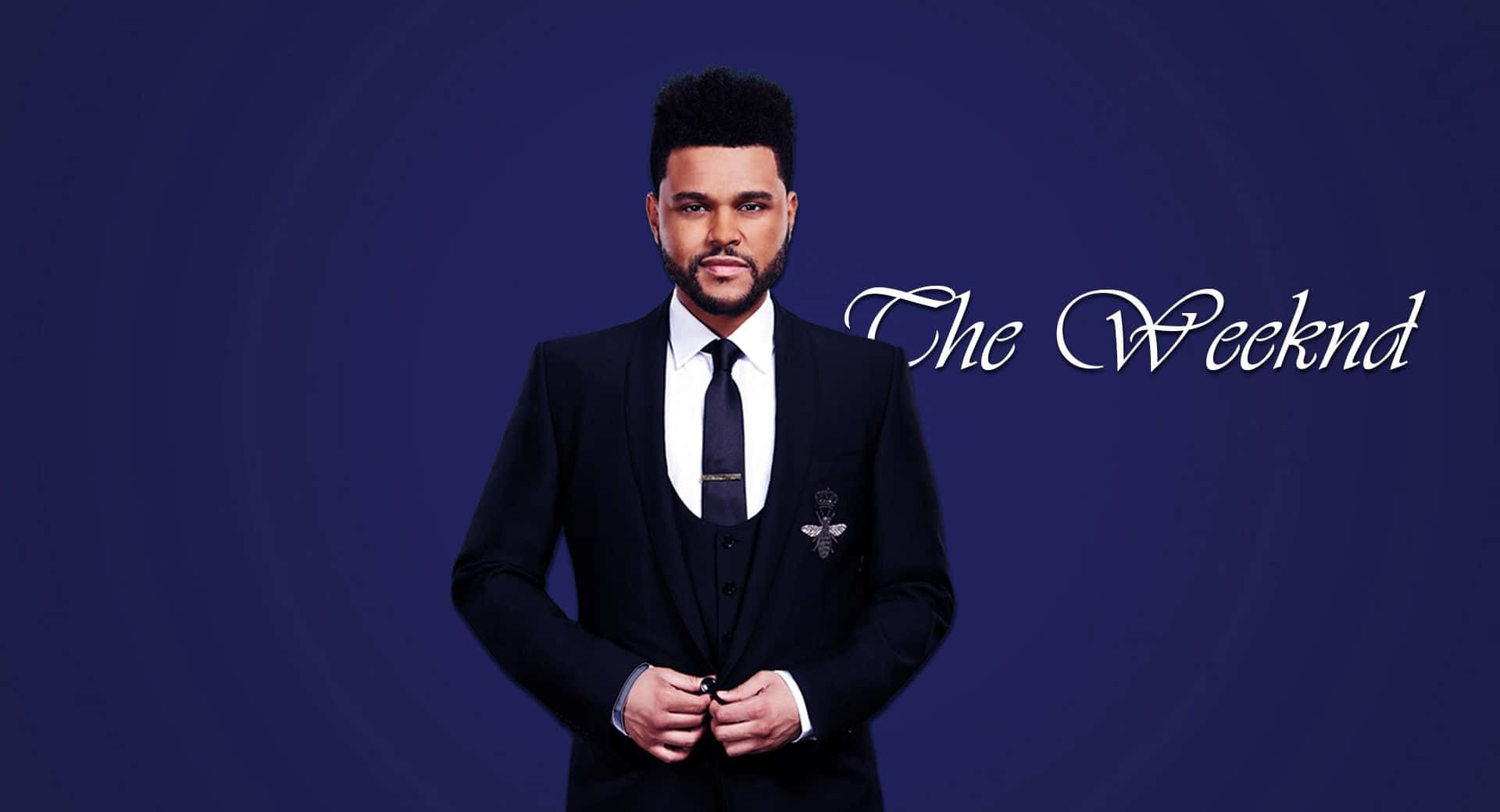 The Weeknd 桌布 壁紙 — The Weeknd 自信地穿著黑色西裝，站在深藍色漸變背景前，他的名字以優雅的白色草書書寫。