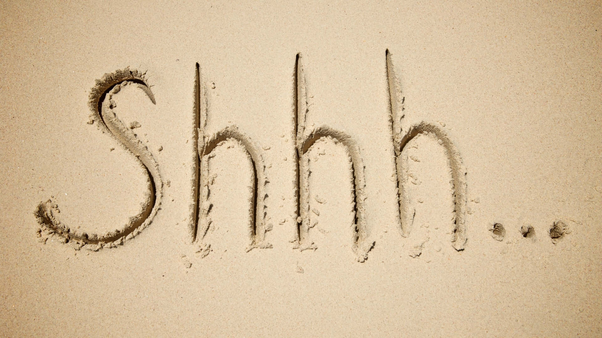  壁紙 — 「Shhh...」呢個字用有紋理嘅筆畫寫喺沙上面，喺米色嘅沙灘表面傳達寧靜。