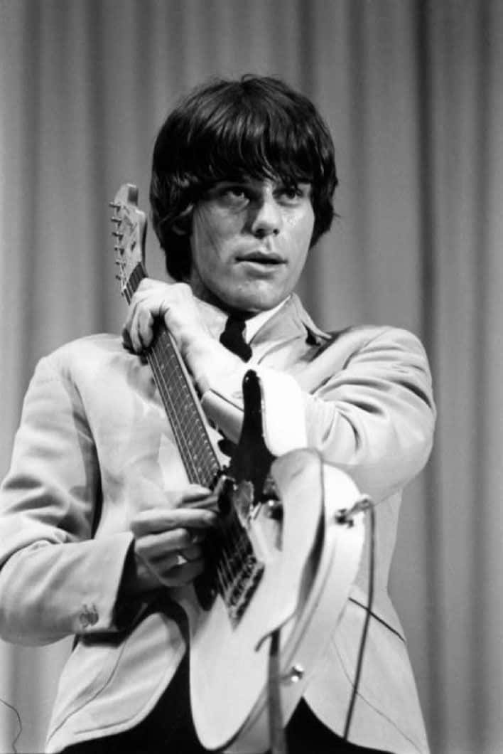 The Yardbirds吉他手Jeff Beck黑白影像 壁紙 — 一張黑白照片，顯示一位頭髮蓬鬆的年輕男子在舞台上拿著電結他。