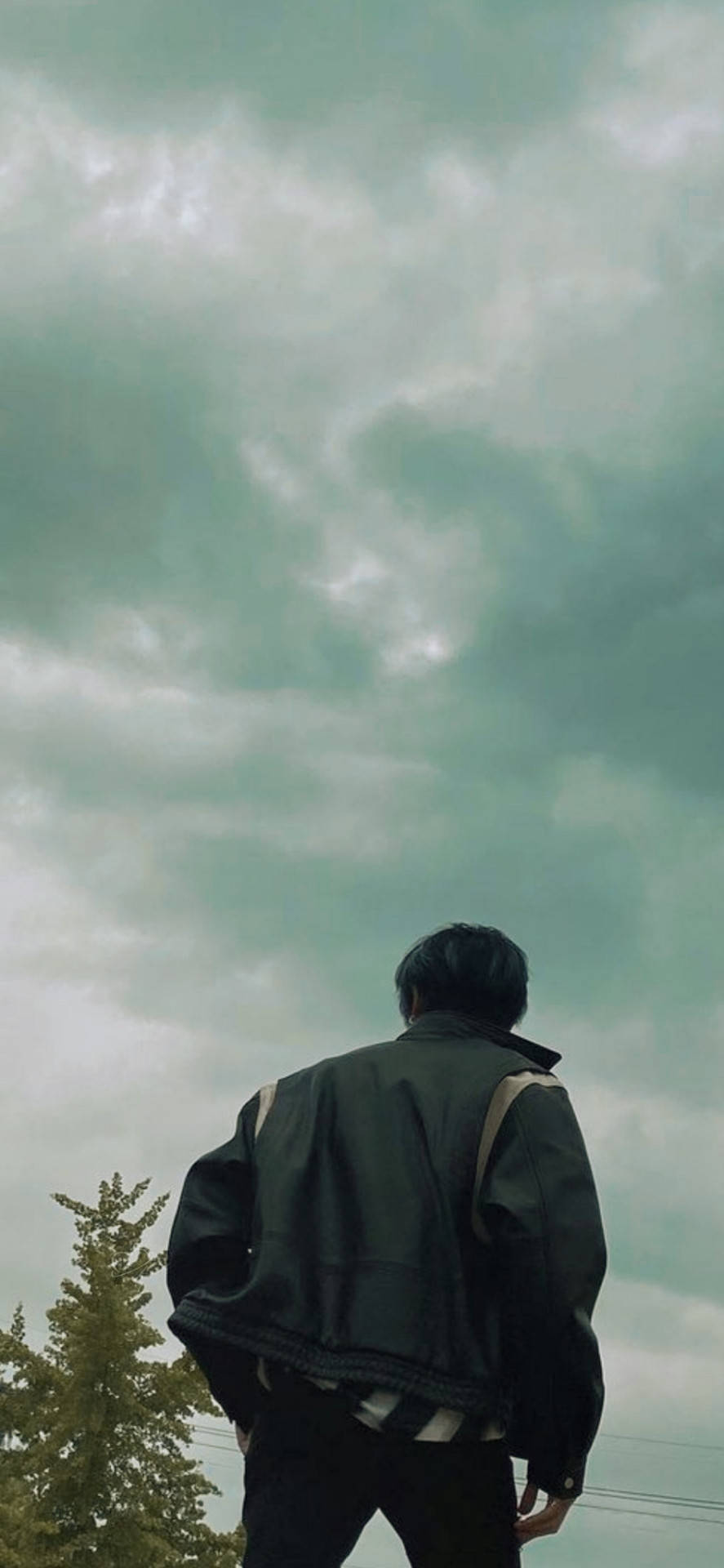 穿深色外套的人仰望多雲的天空