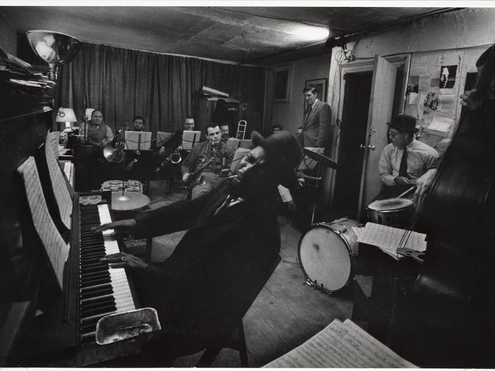 Thelonious Monk 地下演出現場 壁紙 — 一位戴著紳士帽的爵士鋼琴家在昏暗的錄音室中熱情地向後傾斜，他的樂隊正在演奏。