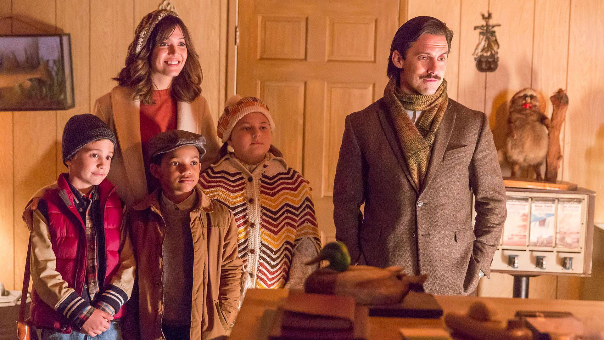 《This Is US》感恩節劇集 壁紙 — 一個五口之家站在一個溫暖照明的木屋中，帶有復古裝飾和一隻標本貓頭鷹在收音機上。