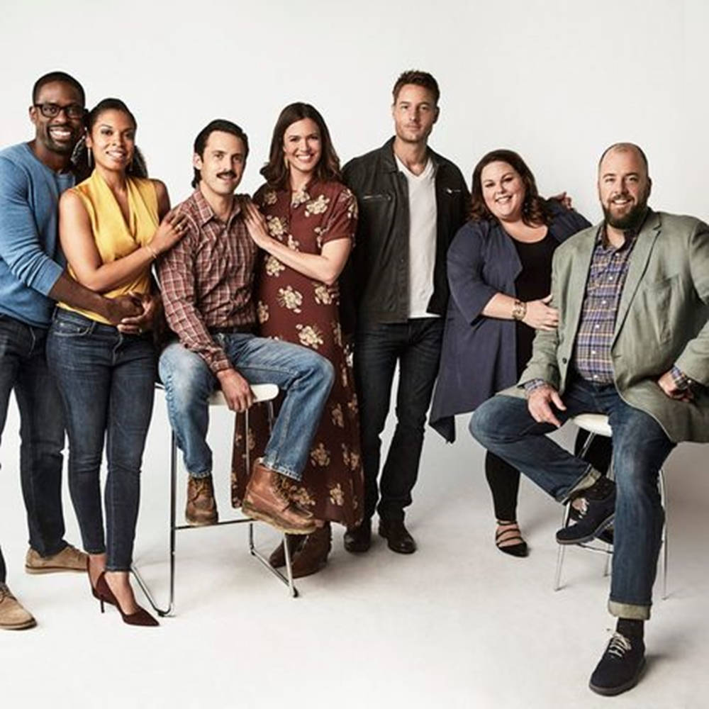《This Is US》第三季拍攝現場 壁紙 — 七位不同種族嘅演員笑住喺白色純色工作室背景前隨意坐喺椅子上擺甫士。