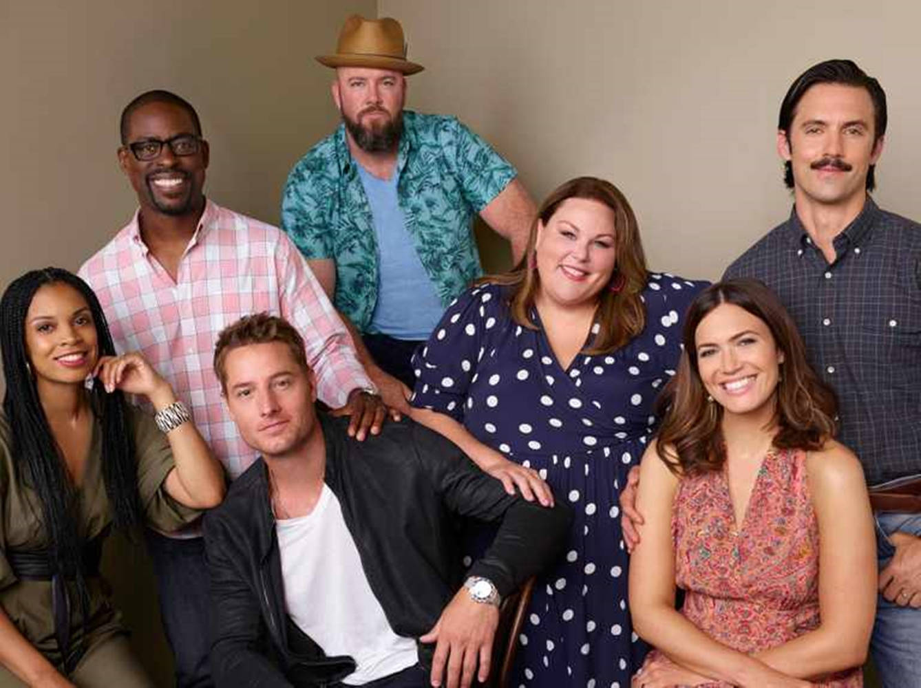 《This Is US》第五季拍攝現場 壁紙 — 六位來自不同背景、面帶笑容的人士在溫暖的攝影棚內，以中性米色牆壁為背景一起擺姿勢。