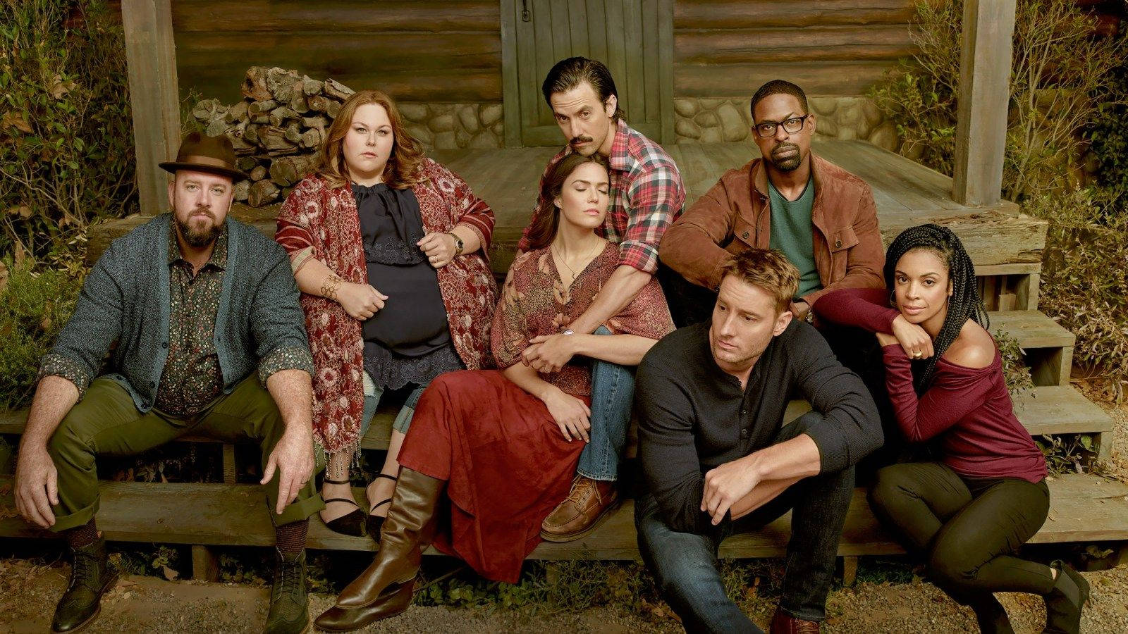 《This Is US》虛構家庭 壁紙 — 七位演員在一個質樸的木製門廊上擺姿勢，身後是一座被秋葉環繞的木屋。