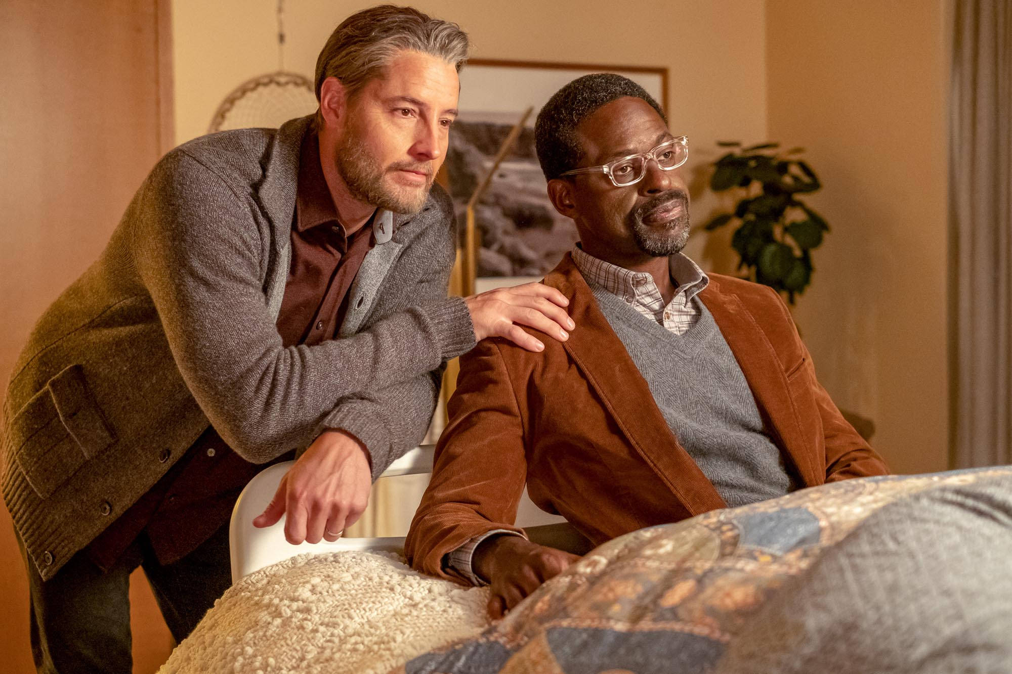 《This Is US》裴森兄弟 壁紙 — 兩個男人在室內共享寧靜時刻，其中一人將手放在另一人的肩膀上，房間燈光溫暖。