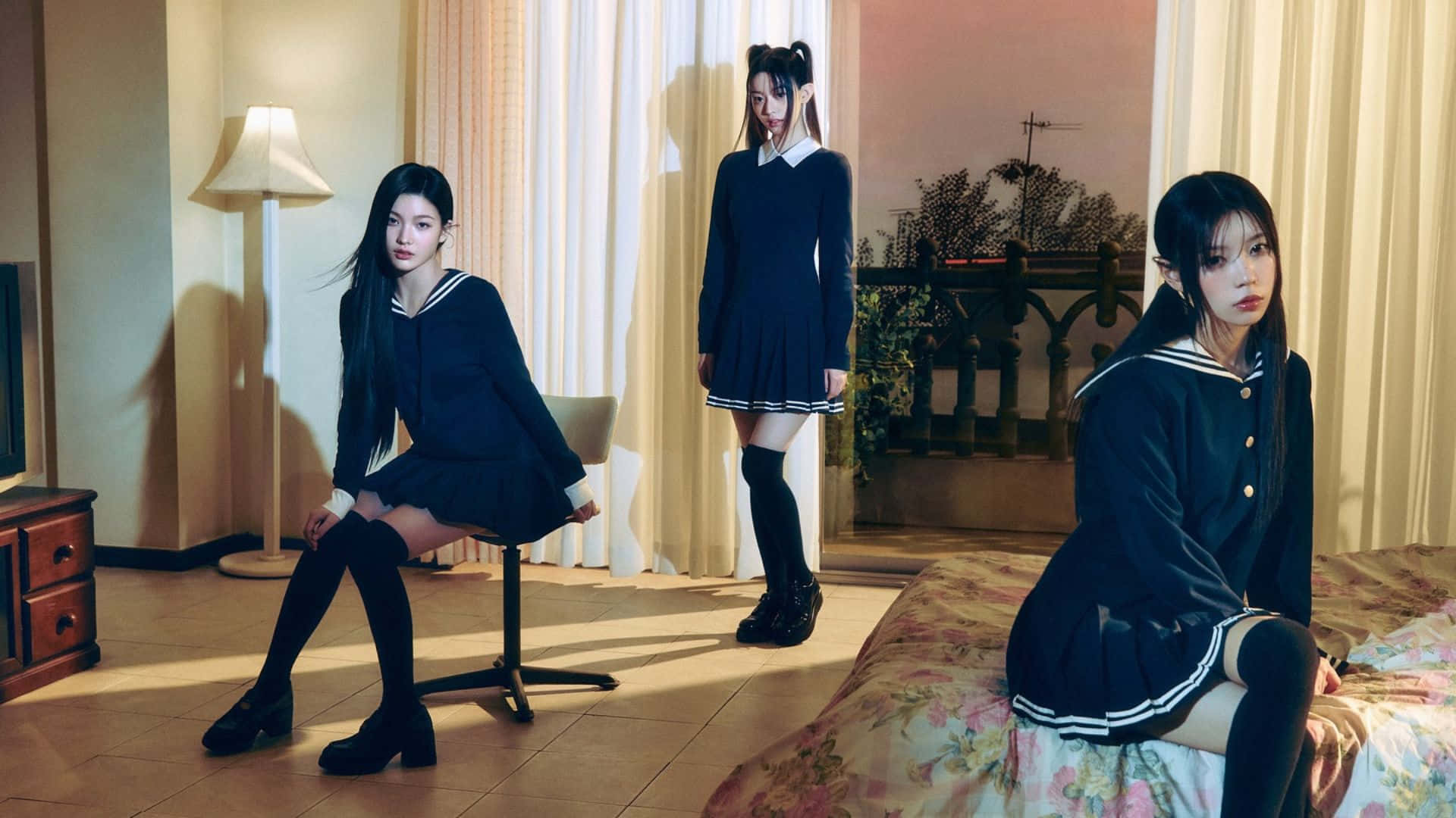  壁紙 — 三個穿著水手服的女孩子在一個燈光溫暖、有花卉床單和薄紗窗簾的房間裡擺姿勢。
