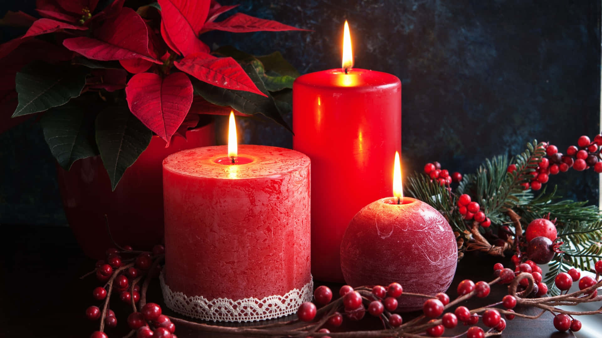  壁紙 — 三支發光的紅色蠟燭依偎在聖誕紅和紅色漿果之間，營造出溫暖喜慶的節日場景。