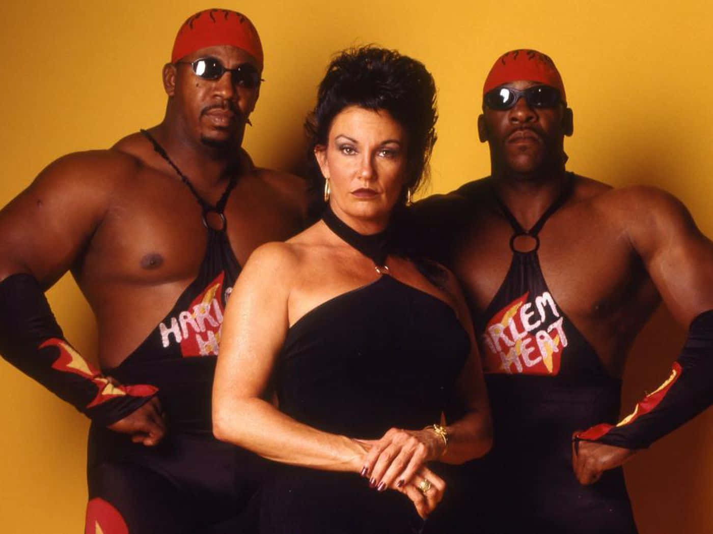  壁紙 — 三名身穿 Harlem Heat 制服的肌肉發達摔角手在純黃色背景前自信地擺姿勢。