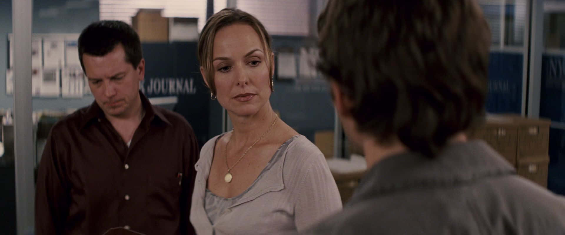 Melora Hardin 桌布 壁紙 — 辦公室裡有三個人，一名女性向前看，兩名男性站在她旁邊。