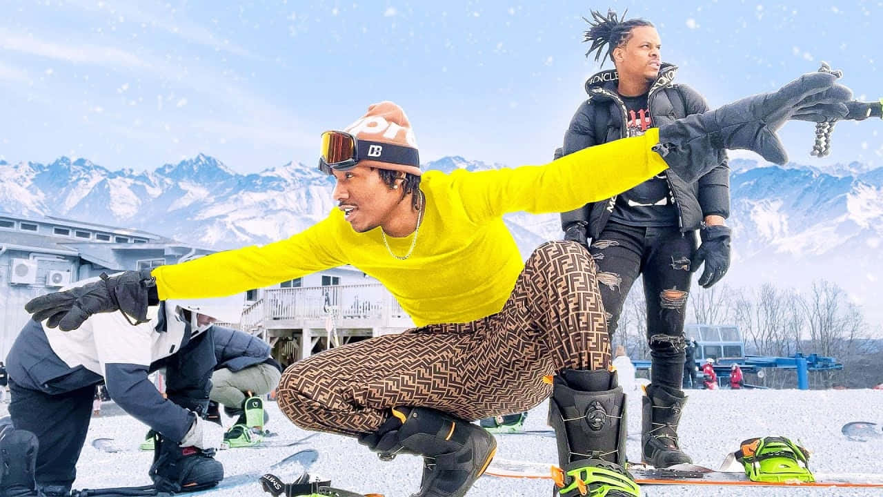 Duke Dennis 桌布 壁紙 — 三名滑雪板手在明亮的藍天下，以積雪覆蓋的山脈為背景，在雪坡上動態地擺姿勢。