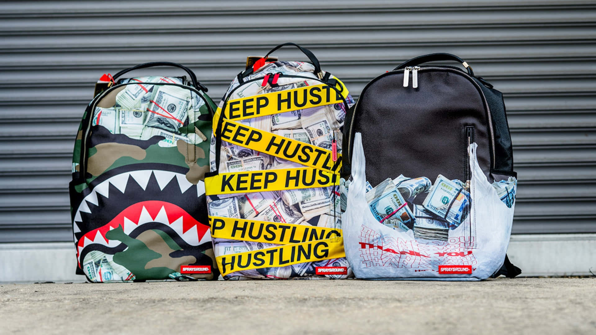  壁紙 — 三個裝滿現金和黃色「KEEP HUSTLING」膠帶的Sprayground背包靠在一扇灰色金屬門上。
