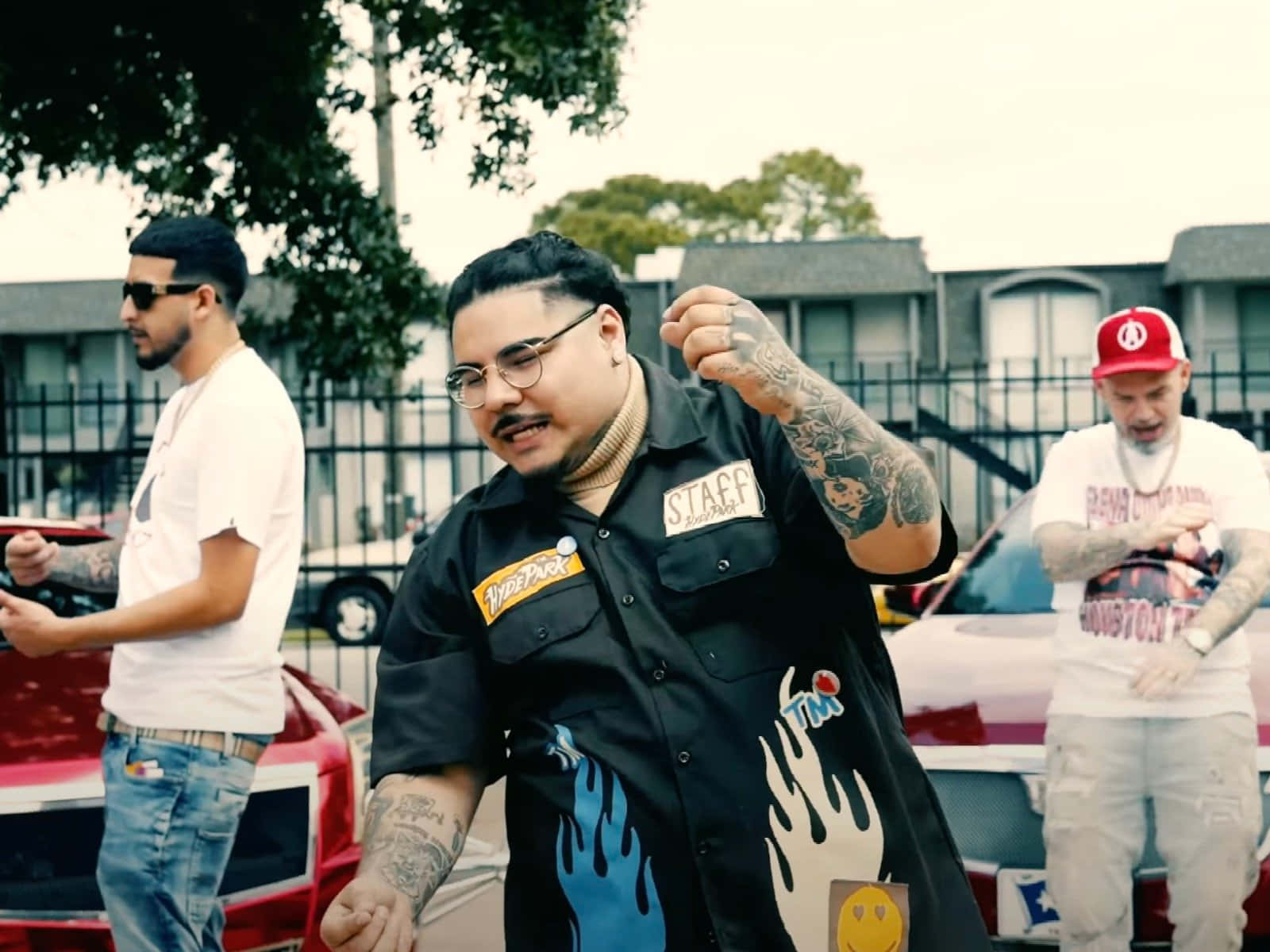  壁紙 — 三位紋身男子穿著休閒街頭服飾，在粗糙的城市停車場中自信地在經典老爺車旁擺姿勢。