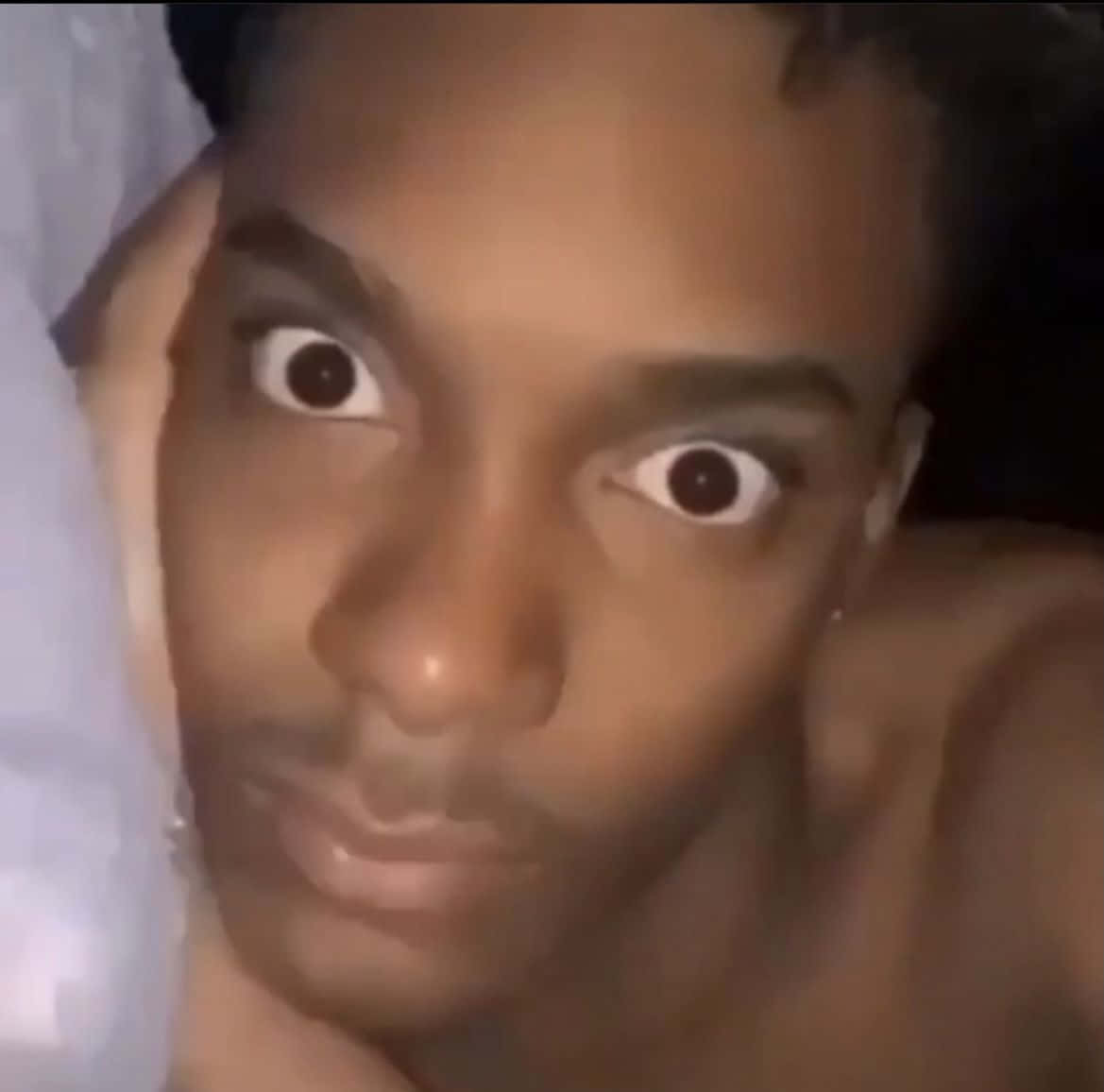 TikTok男搞笑表情包圖片 壁紙 — 一個人在昏暗環境中睜大眼睛直視鏡頭的特寫。