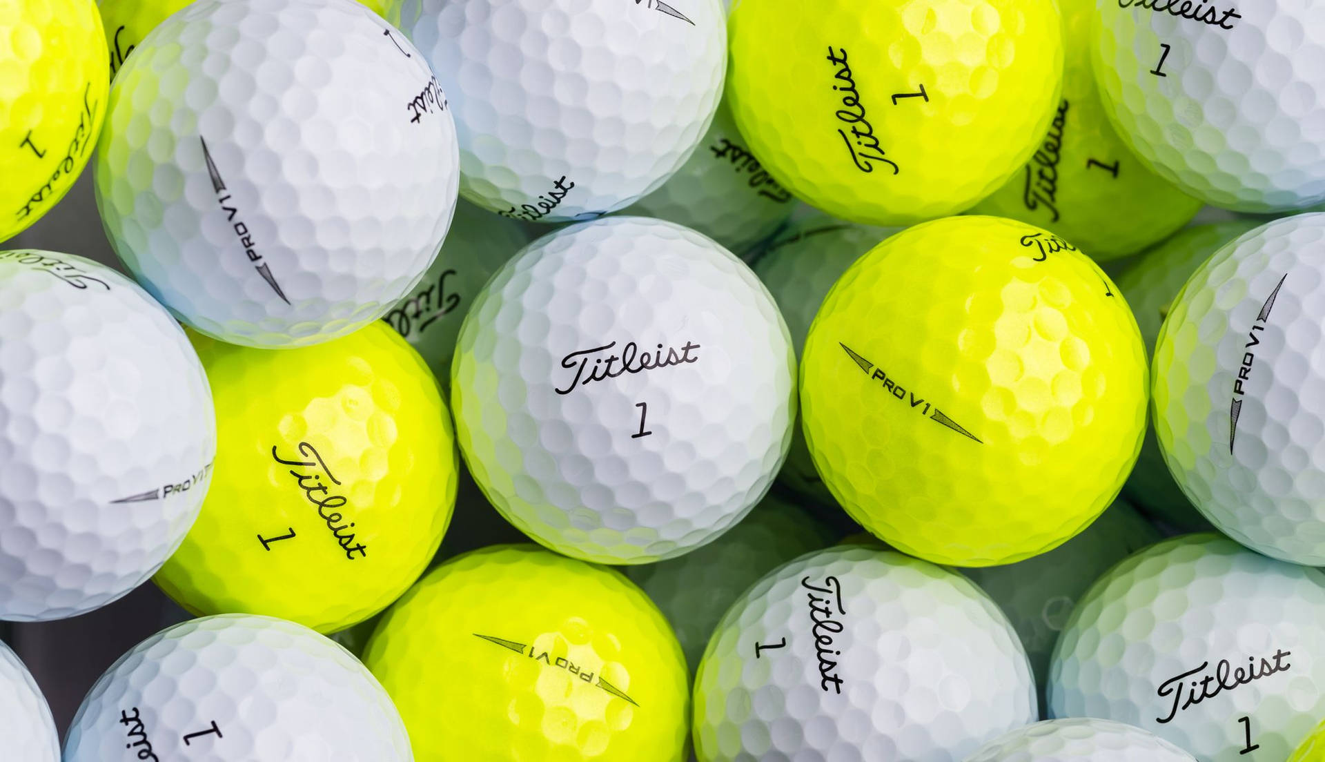 一堆白色和黃色 Titleist 高爾夫球，帶有凹痕紋理。