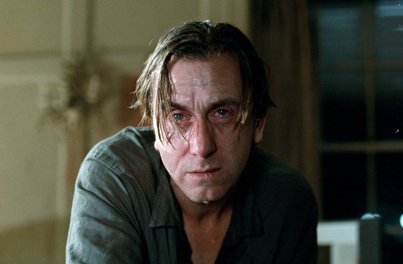 Tim Roth 飾 乔治法伯《趣味遊戲》 壁紙 — 一個頭髮濕透、臉上帶淚痕的男人，在身後有窗戶的昏暗房間裏凝視着。