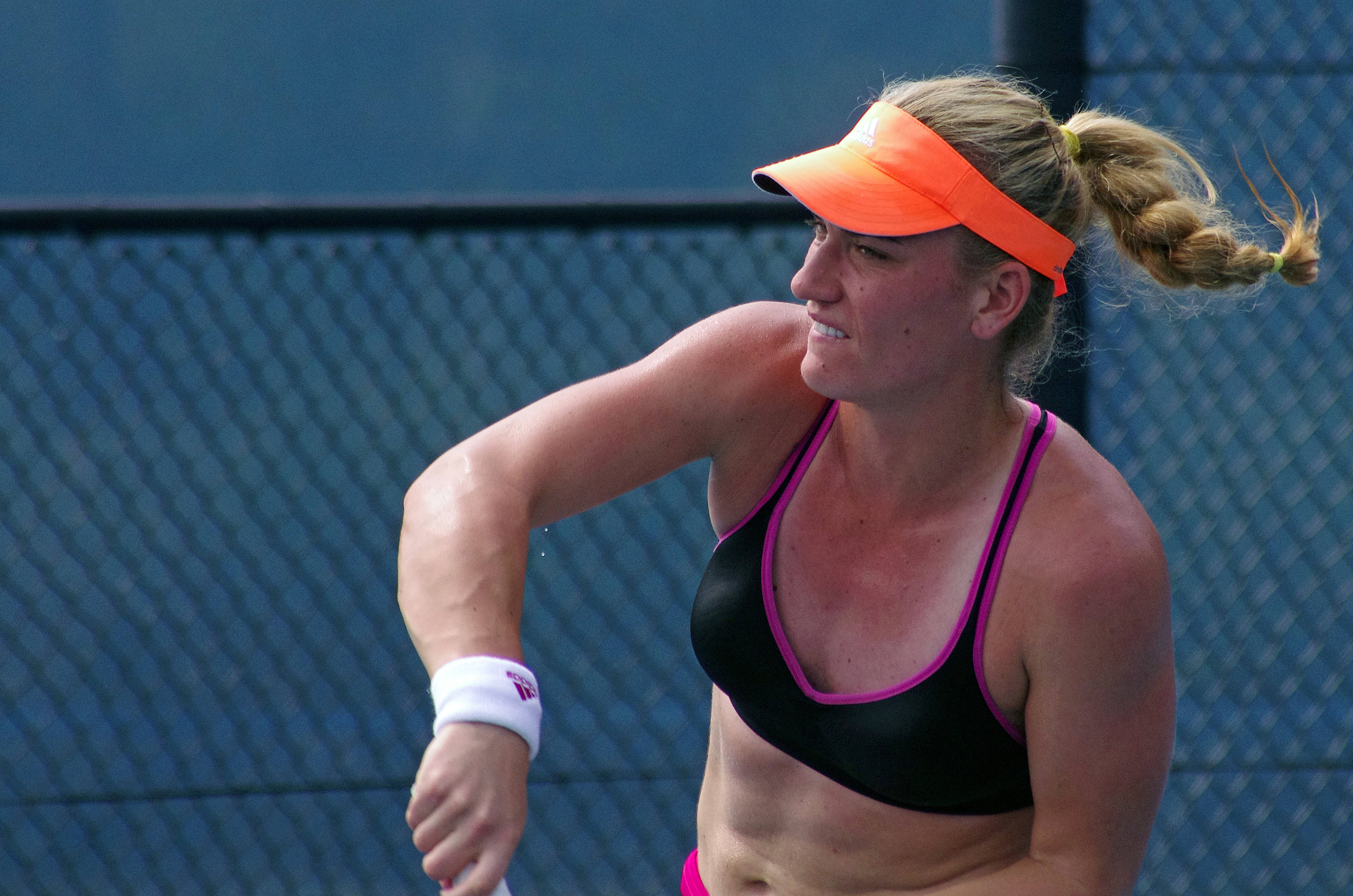 Timea Babos 完成強力揮拍後 壁紙 — 一位專注的女網球手正在揮拍，戴著橙色遮陽帽和黑色運動上衣，背景是藍色鐵絲網圍欄。