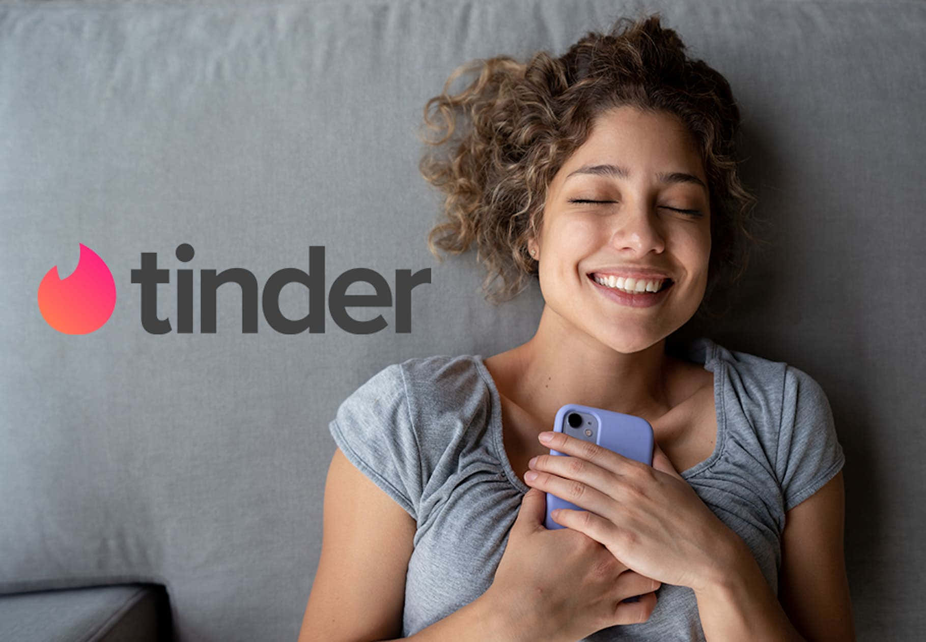 女性在灰色沙發上拿著手機微笑，Tinder 標誌可見