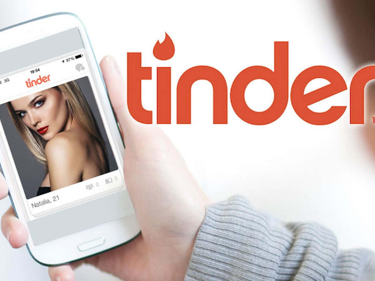 手拿著電話顯示Natalia 21的Tinder約會應用程式個人資料。