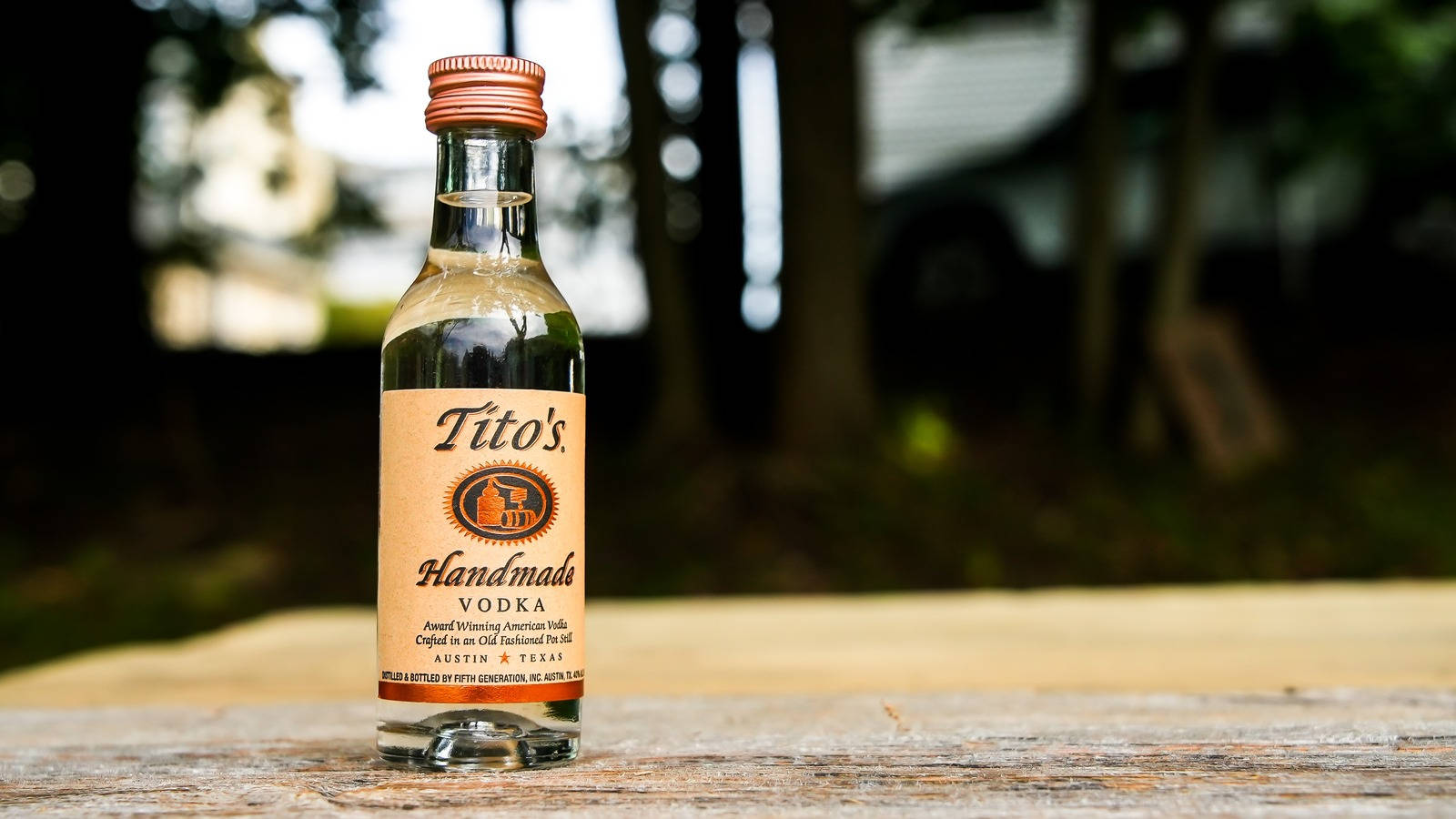 戶外木桌上的小瓶Tito's Handmade Vodka。