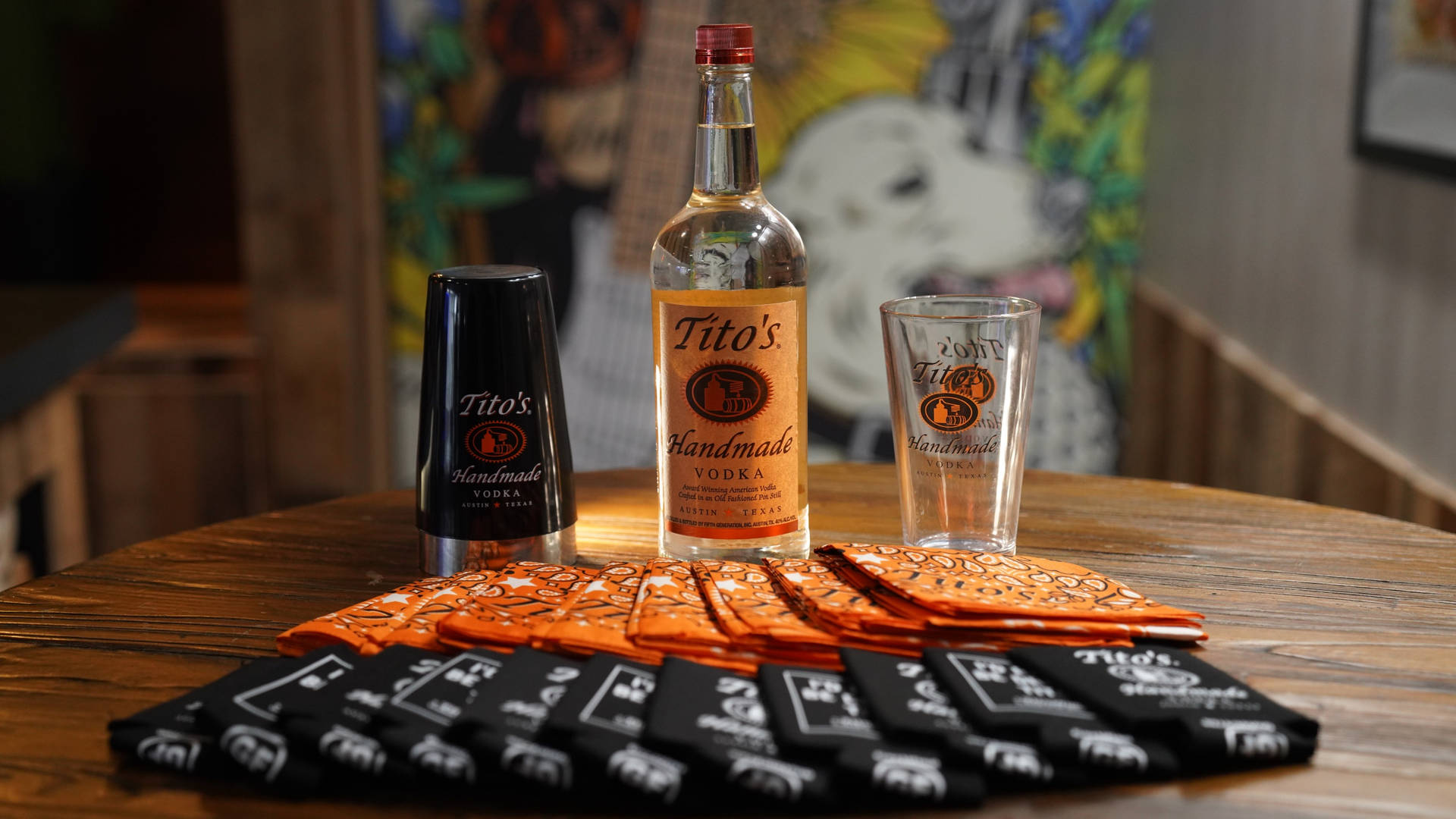Tito's伏特加酒瓶和玻璃杯放在木製吧枱上，配有品牌餐巾。