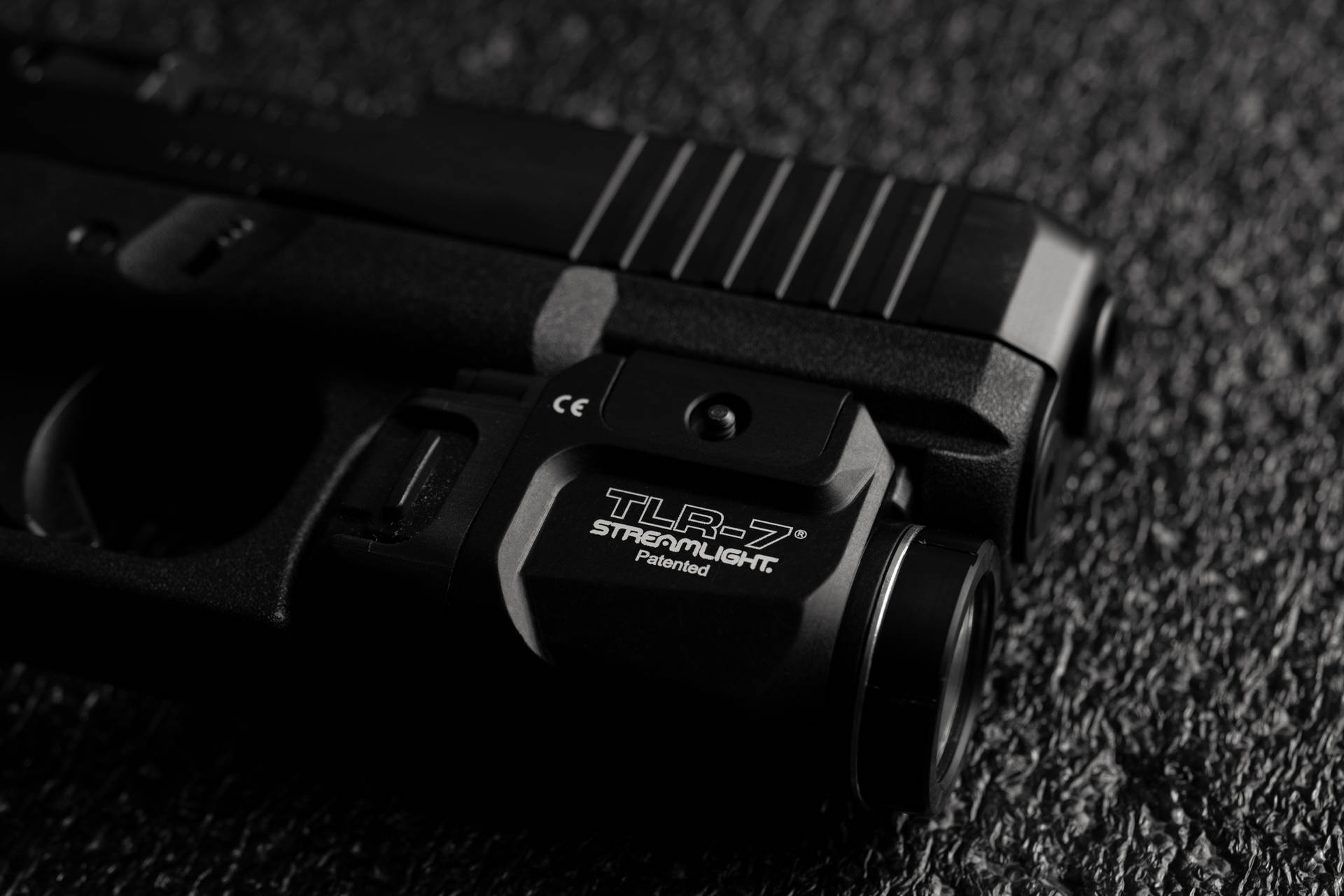 黑色手槍配備 Streamlight TLR-7 激光瞄準器，置於紋理表面。