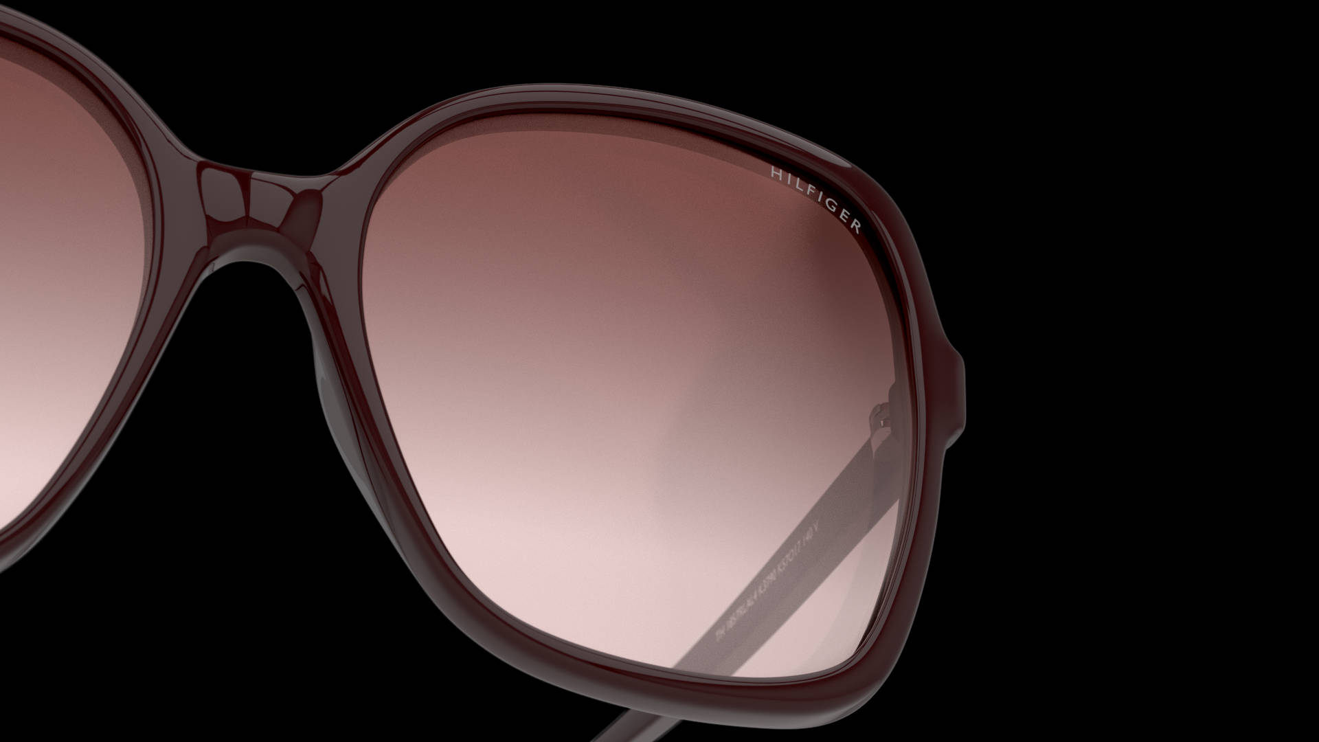 Tommy Hilfiger TH 1857 經典太陽眼鏡 壁紙 — 酒紅色光面太陽眼鏡配漸變粉紅色鏡片，在純黑色背景上的特寫。