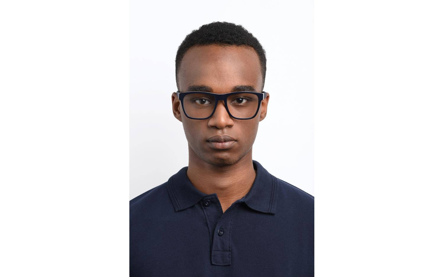 Tommy Hilfiger 男模特 壁紙 — 一位短黑髮、戴著大膽黑色粗框眼鏡的年輕男子，在純白背景前直視鏡頭。