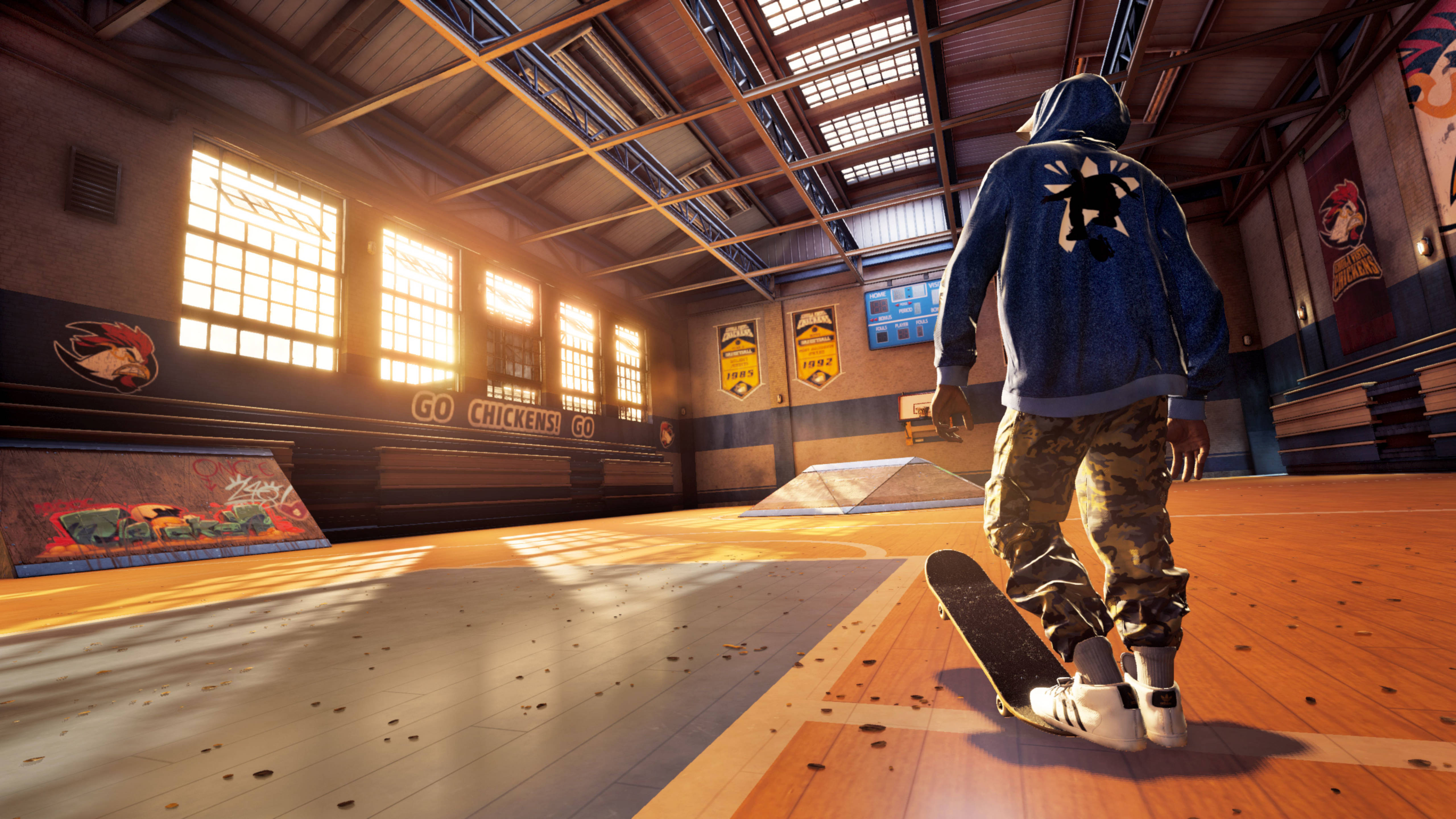 Tony Hawk Pro Skater 健身房 壁紙 — 一名身穿藍色連帽衫的滑板手走向一個陽光普照的室內滑板公園，內有木製坡道和塗鴉牆。