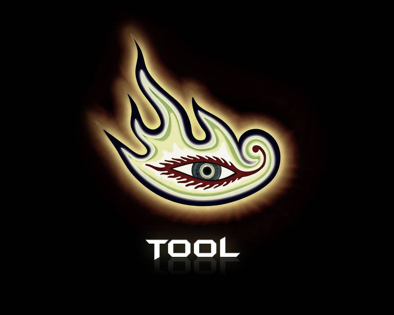 凝視Tool樂團的燃燒之眼 壁紙 — 一個發光的風格化眼睛，帶有火焰般的翅膀，在黑色背景上散發光芒，下方有「TOOL」字樣。