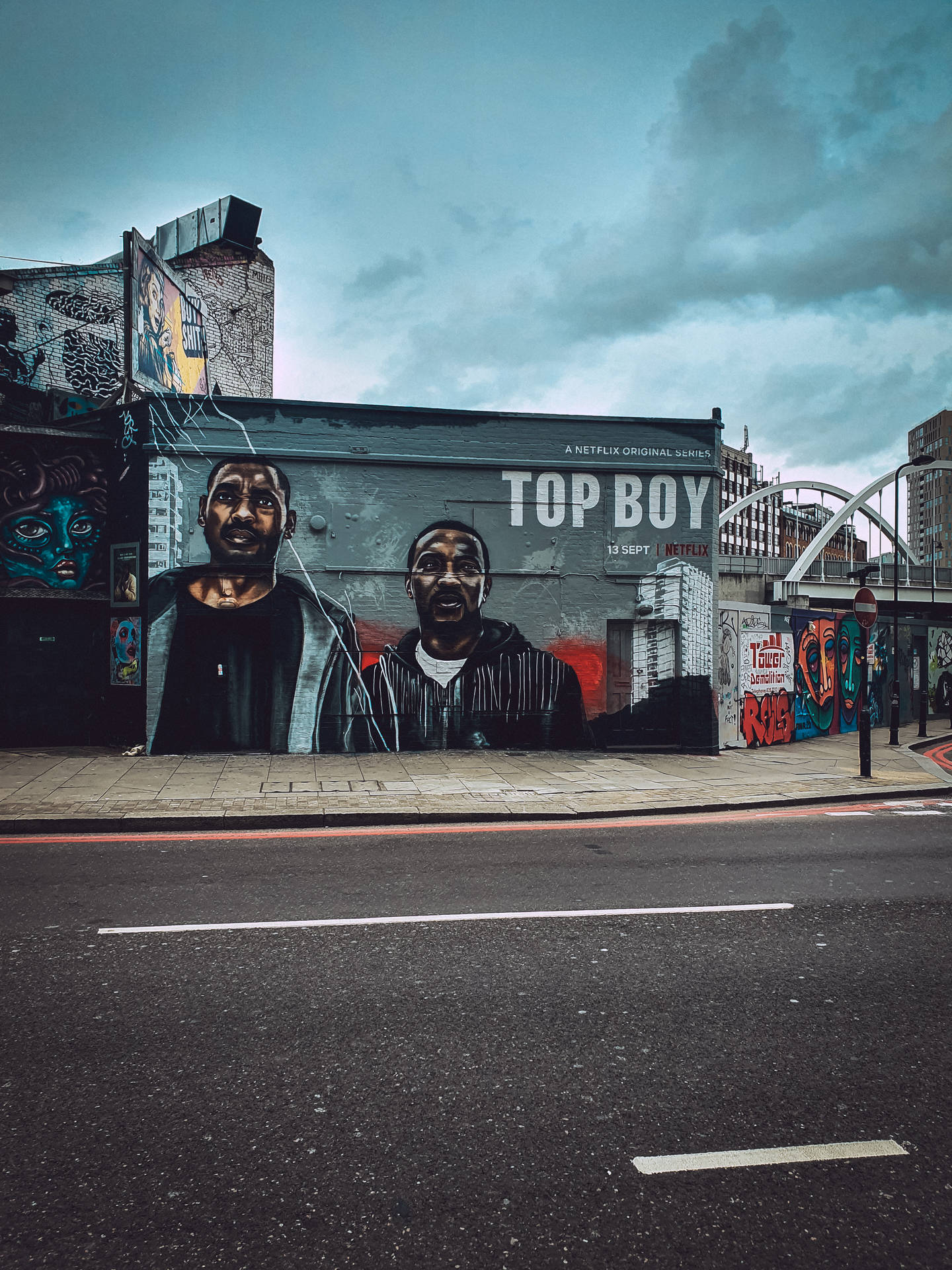 陰天下城市建築物上的《Top Boy》角色街頭壁畫。