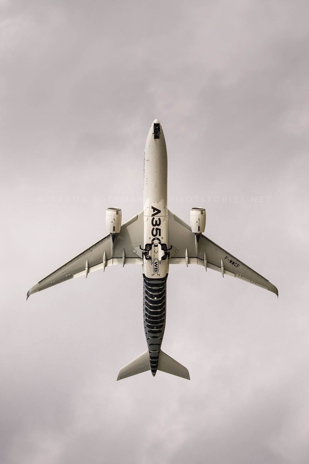 從下方觀看空中巴士A350飛機，背景為多雲天空。