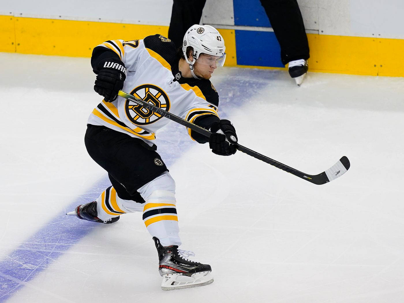 Torey Krug 嘗試射門得分 壁紙 — 一名身穿黑色和黃色裝備的曲棍球運動員在比賽中拿著球棍在冰上激烈滑行。