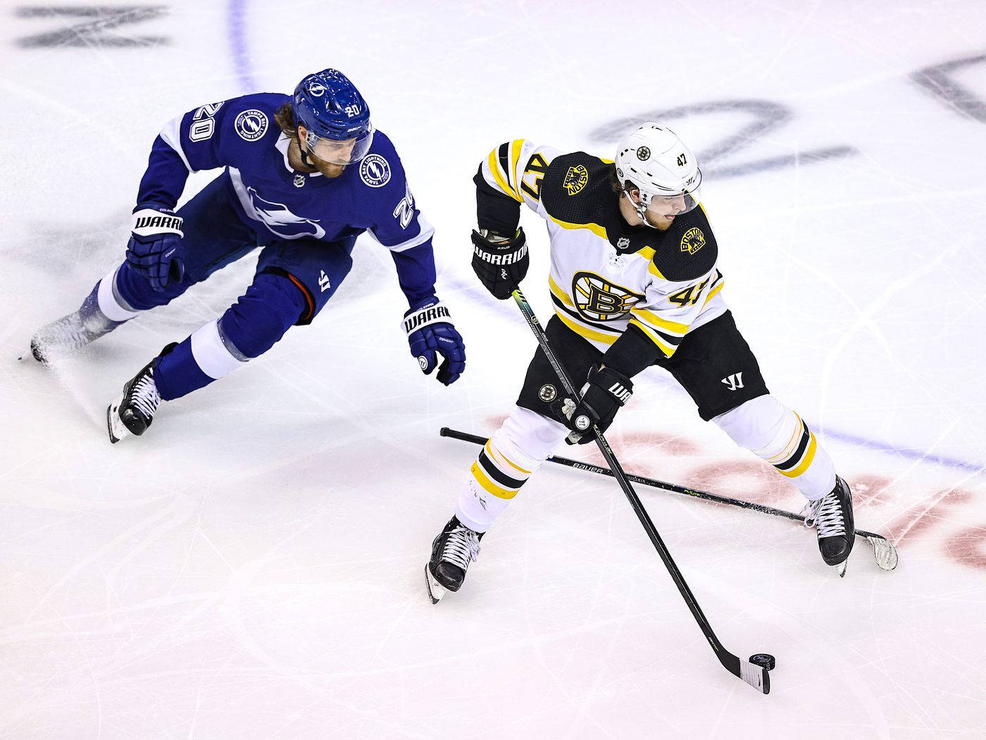 Torey Krug 與 Blake Coleman 壁紙 — 兩名曲棍球運動員在佈滿劃痕的冰場上，在明亮的場館燈光下激烈爭奪球權。