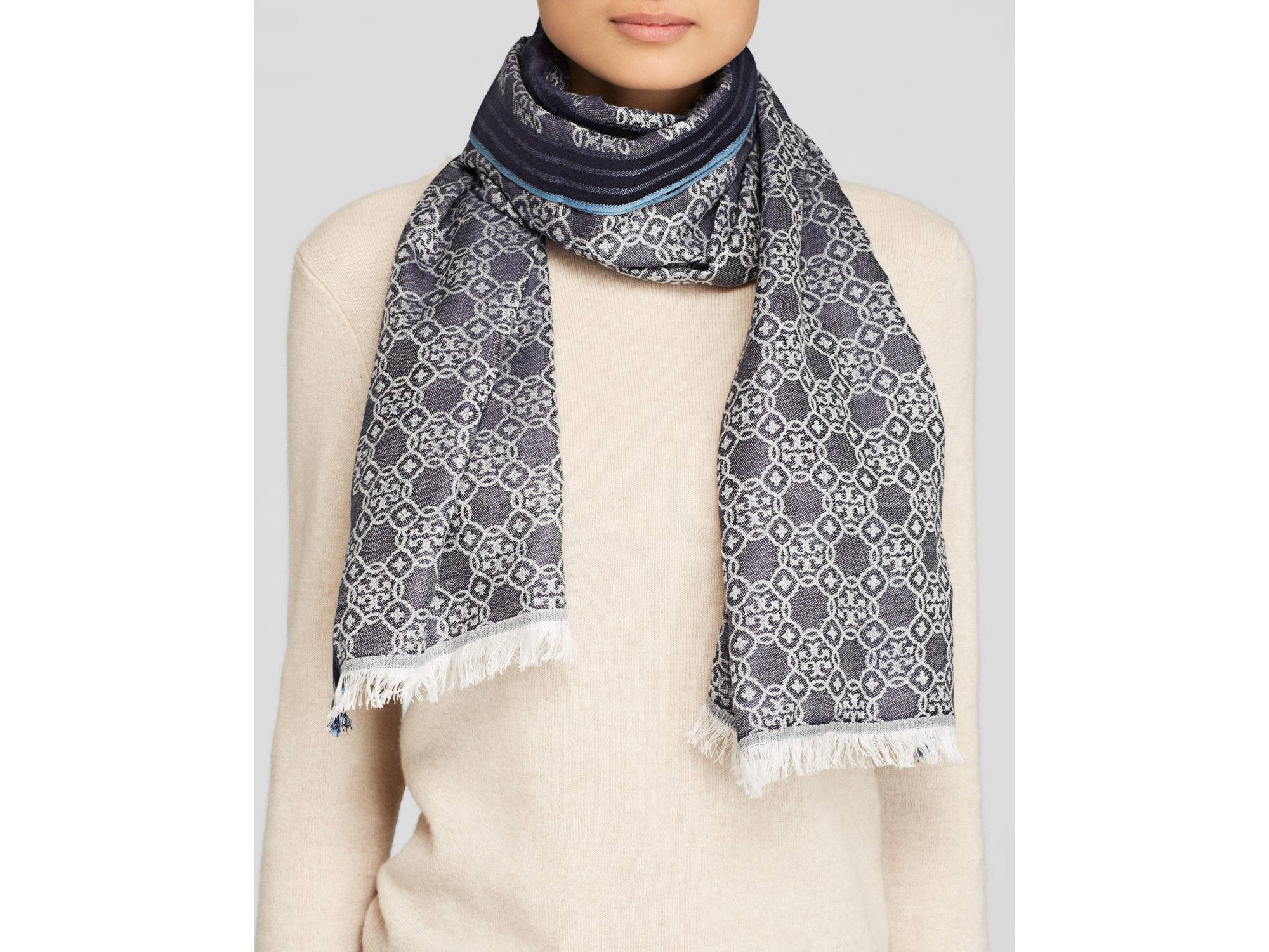 Tory Burch 馬賽克標誌圍巾 壁紙 — 一個人喺忌廉色毛衣上面戴住一條有幾何圖案同流蘇邊嘅圖案圍巾。