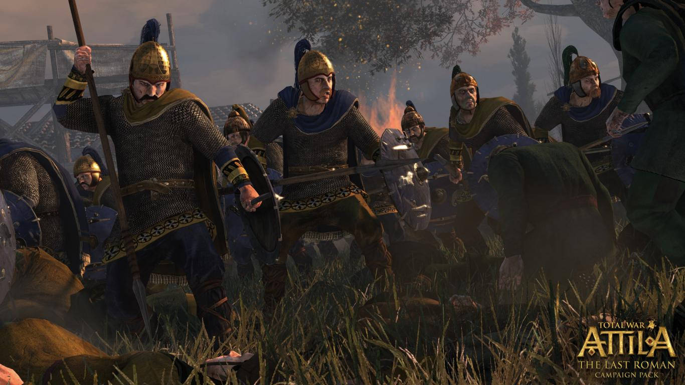 Total War Attila 猛烈戰士 壁紙 — 身穿鎖子甲和頭盔的羅馬士兵在緊張的戰場場景中穿過高草，背景有煙霧和火焰。