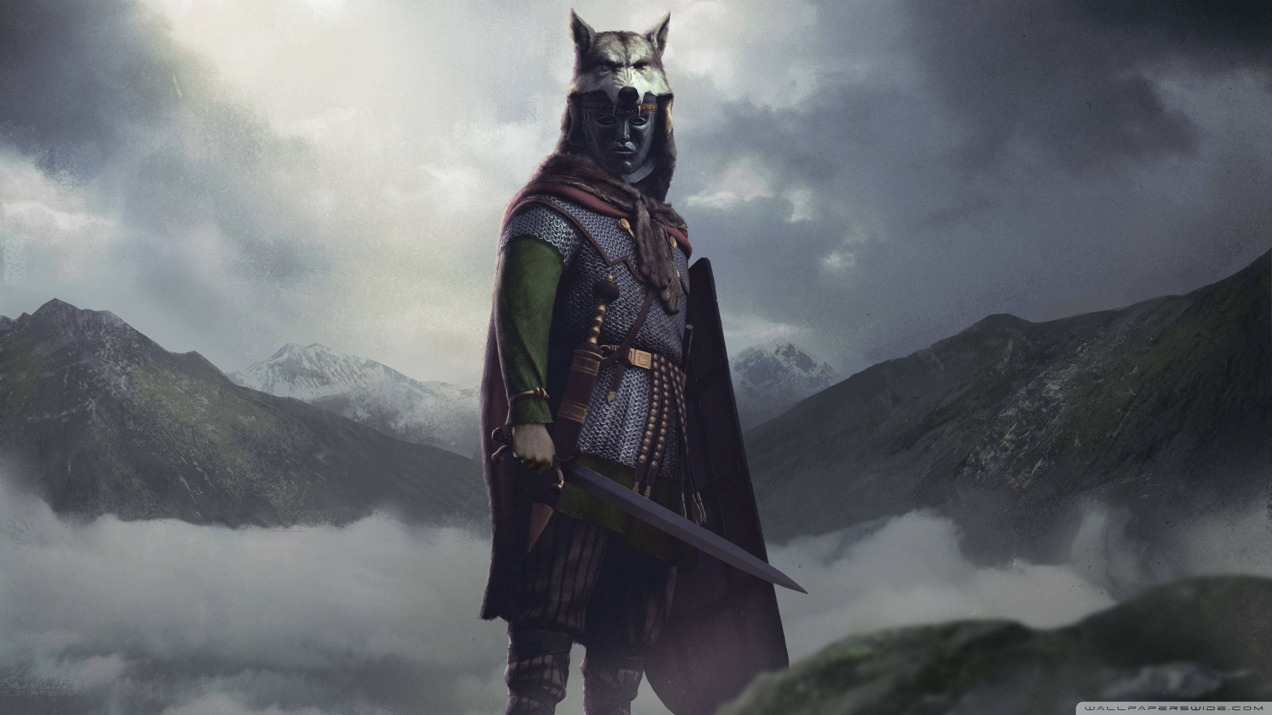 Total War: Attila 狼頭戰士 壁紙 — 一個狼頭戰士身穿鎖子甲和斗篷，站在霧氣籠罩的山頂上，在暴風雨的天空下舉著劍。