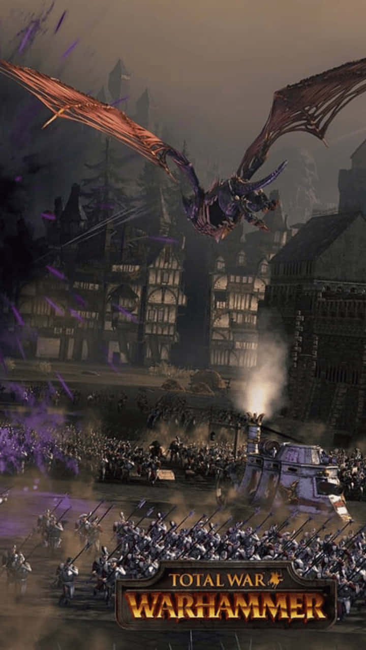 《Total War Warhammer II》移動版 壁紙 — 一條巨龍在一個被圍困的中世紀城市上空翱翔，下方軍隊在混亂的戰鬥場景中交戰。