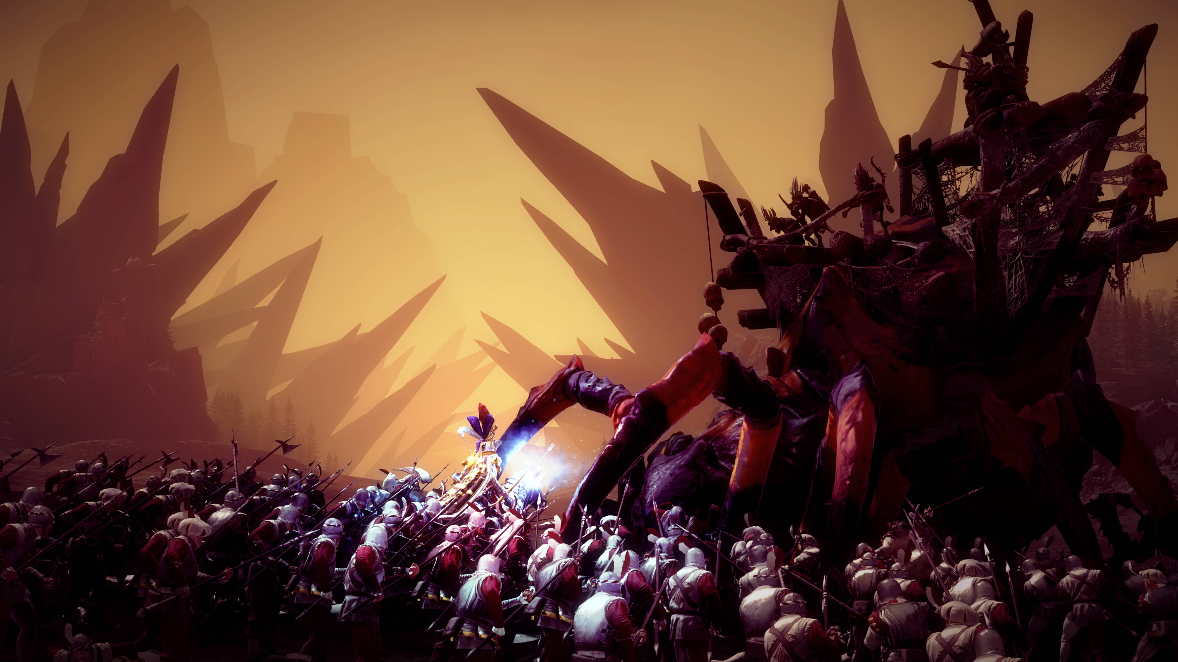 Total War Warhammer 2 阿拉克納洛克蜘蛛 壁紙 — 一個巨大的裝甲生物在發光的橙色天空下，背景有鋸齒狀的山脈，與一群士兵戰鬥。