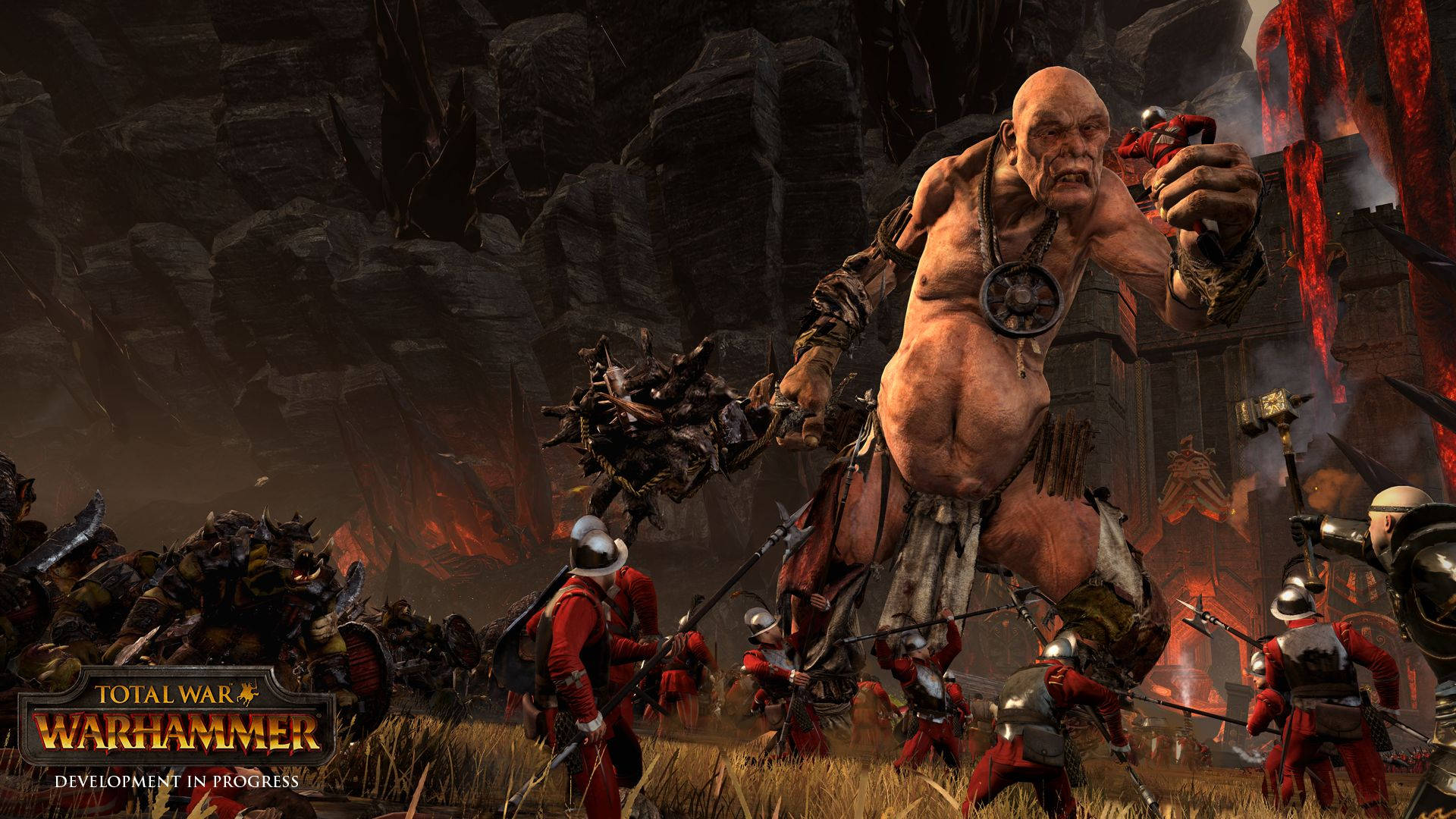 Total War Warhammer 2 巨人 壁紙 — 一個巨大的獸人 warlord 在火焰戰場上揮舞著帶刺的棍棒，周圍是身穿紅色制服的裝甲士兵。