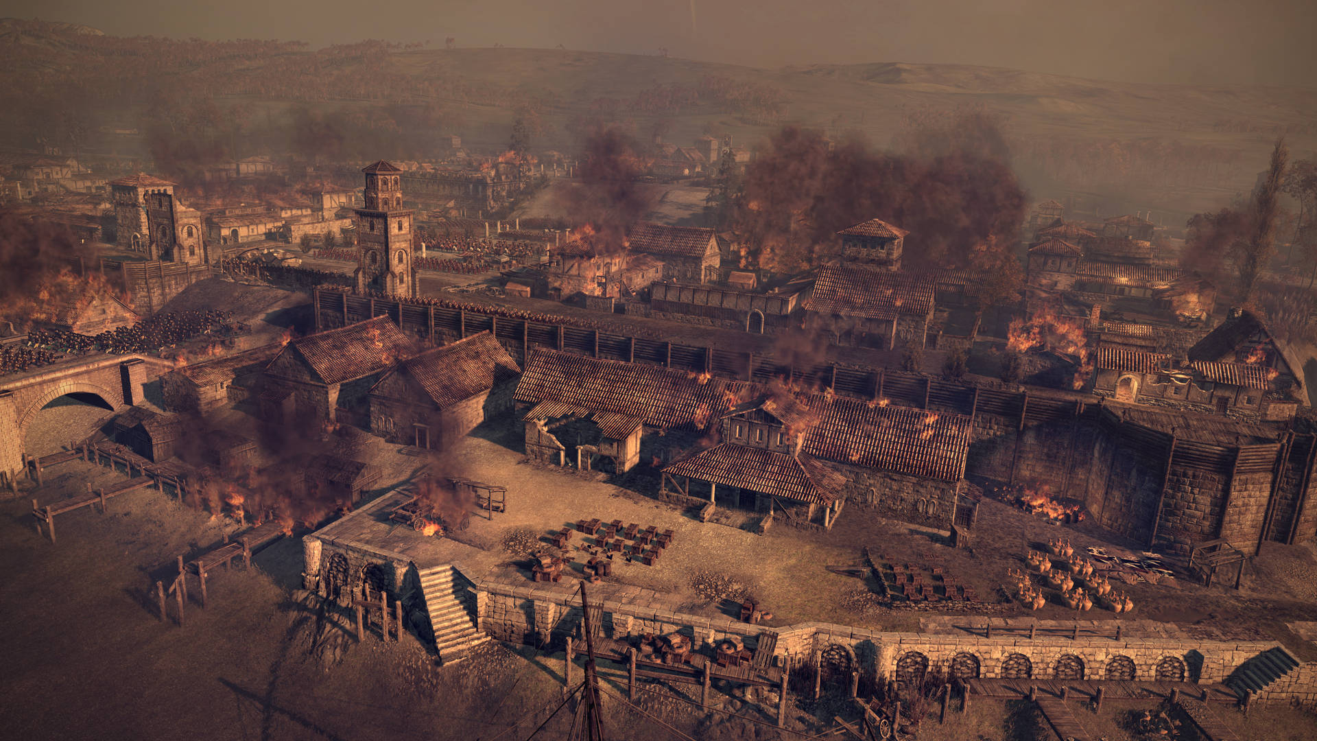 Total War：阿提拉 燃燒的村莊 壁紙 — 一個中世紀村莊猛烈燃燒，多處火災產生的煙霧升騰，吞噬著木建築和石結構。